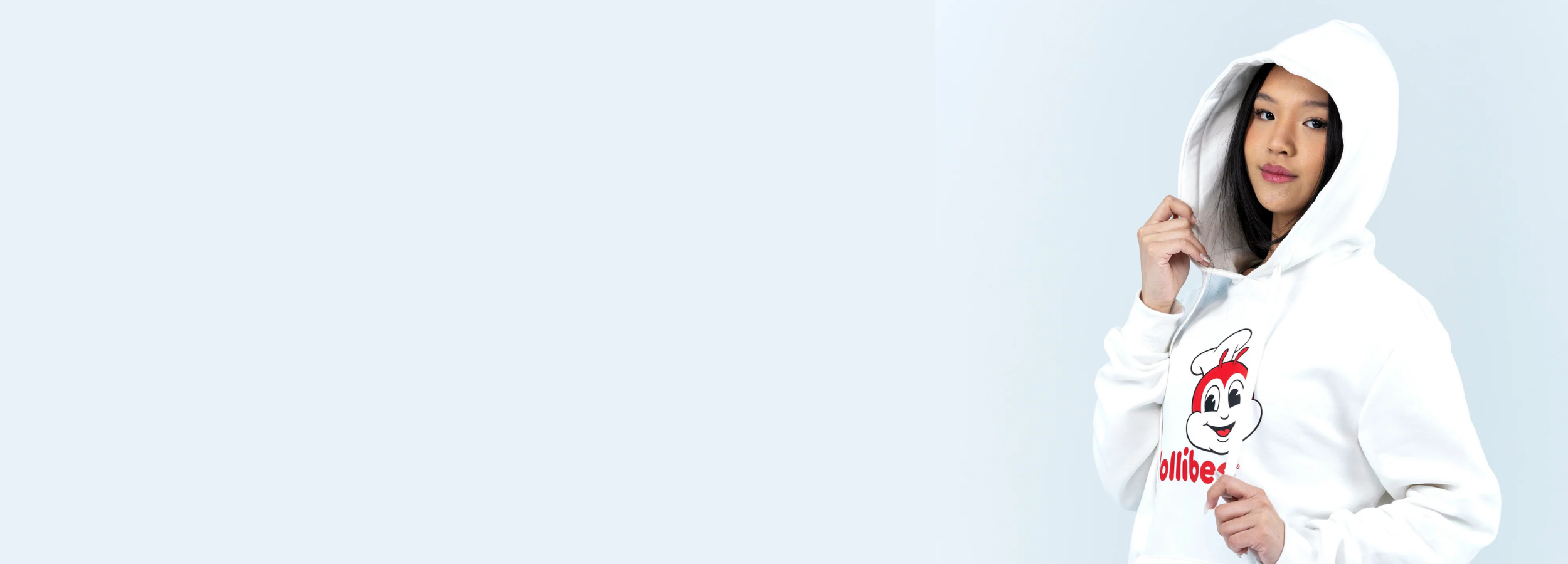 Person wearing a white hoodie with a Jollibee logo on a light blue background