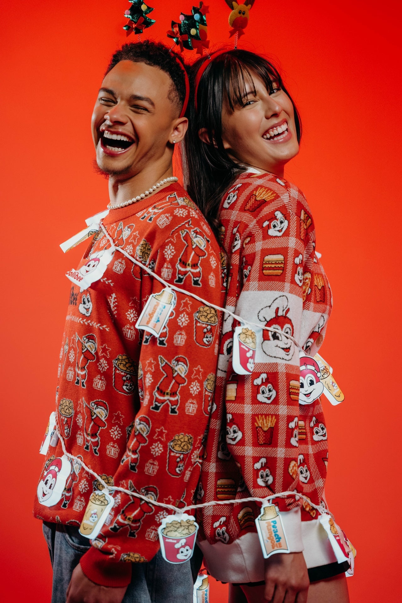 Two people wearing red patterned shirts with tags against a red background