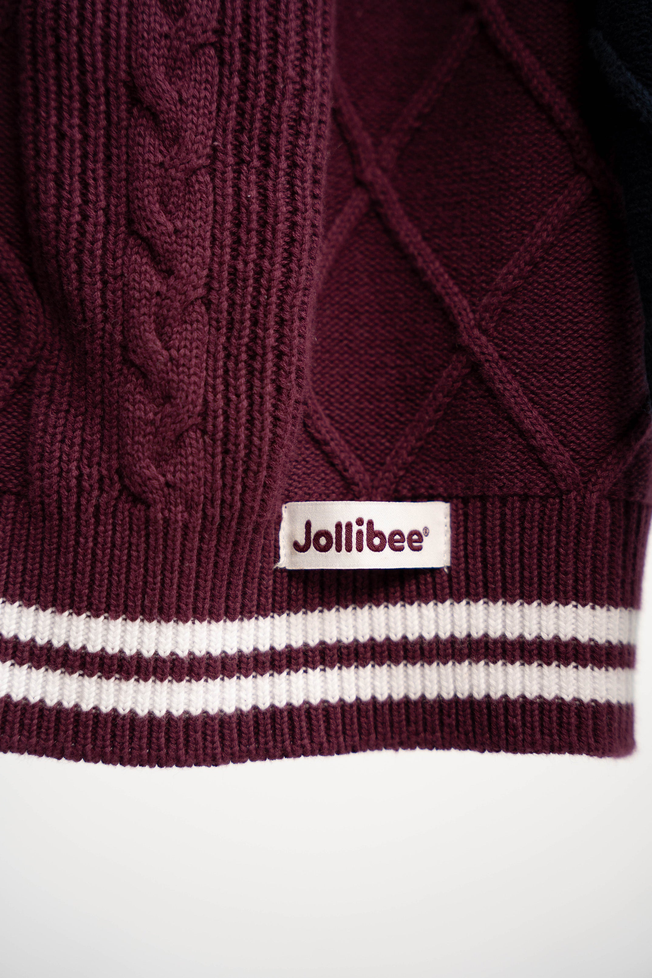 Maroon sweater with cable knit pattern and Jollibee logo on a white background