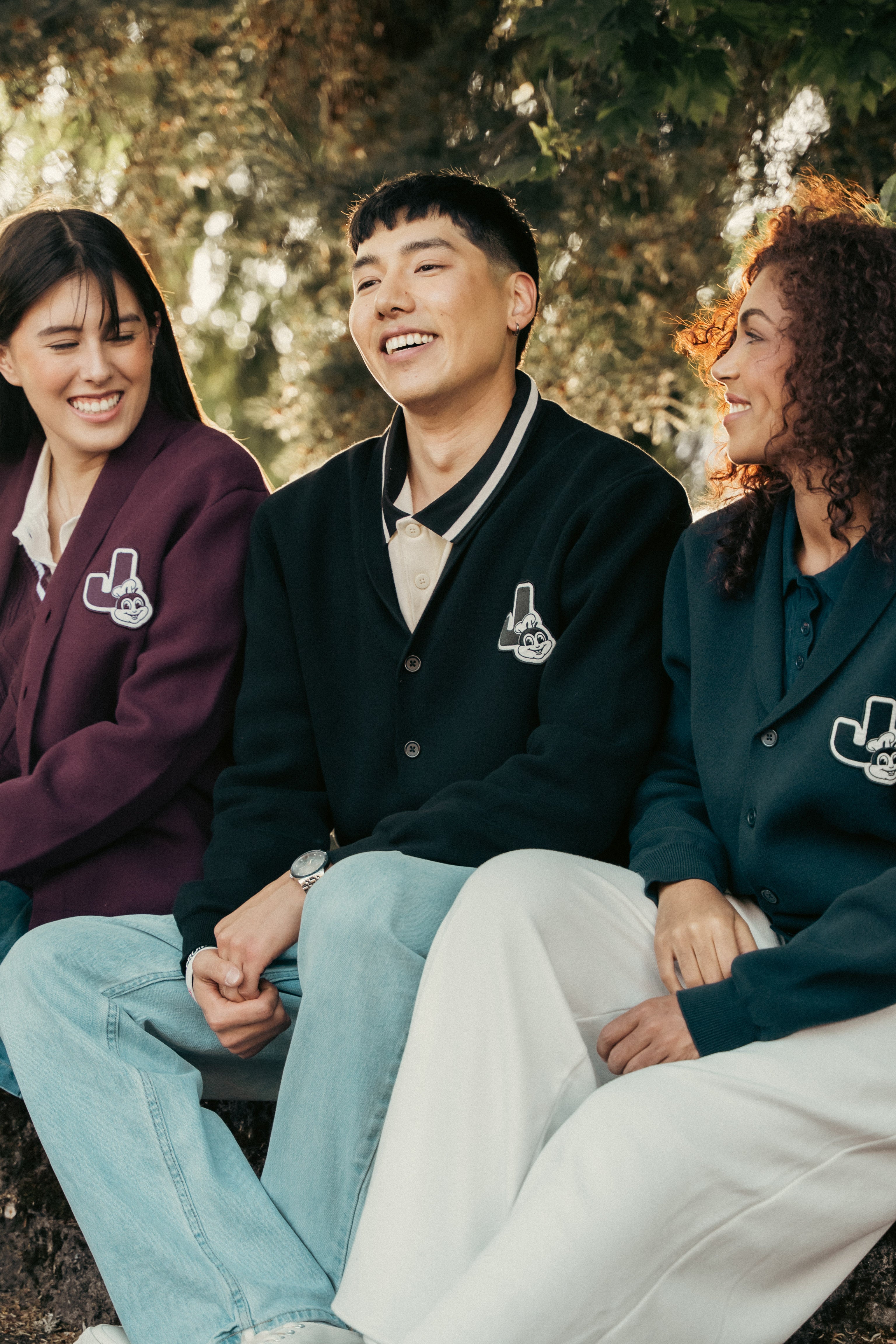 Three people wearing matching cardigans sitting outdoors