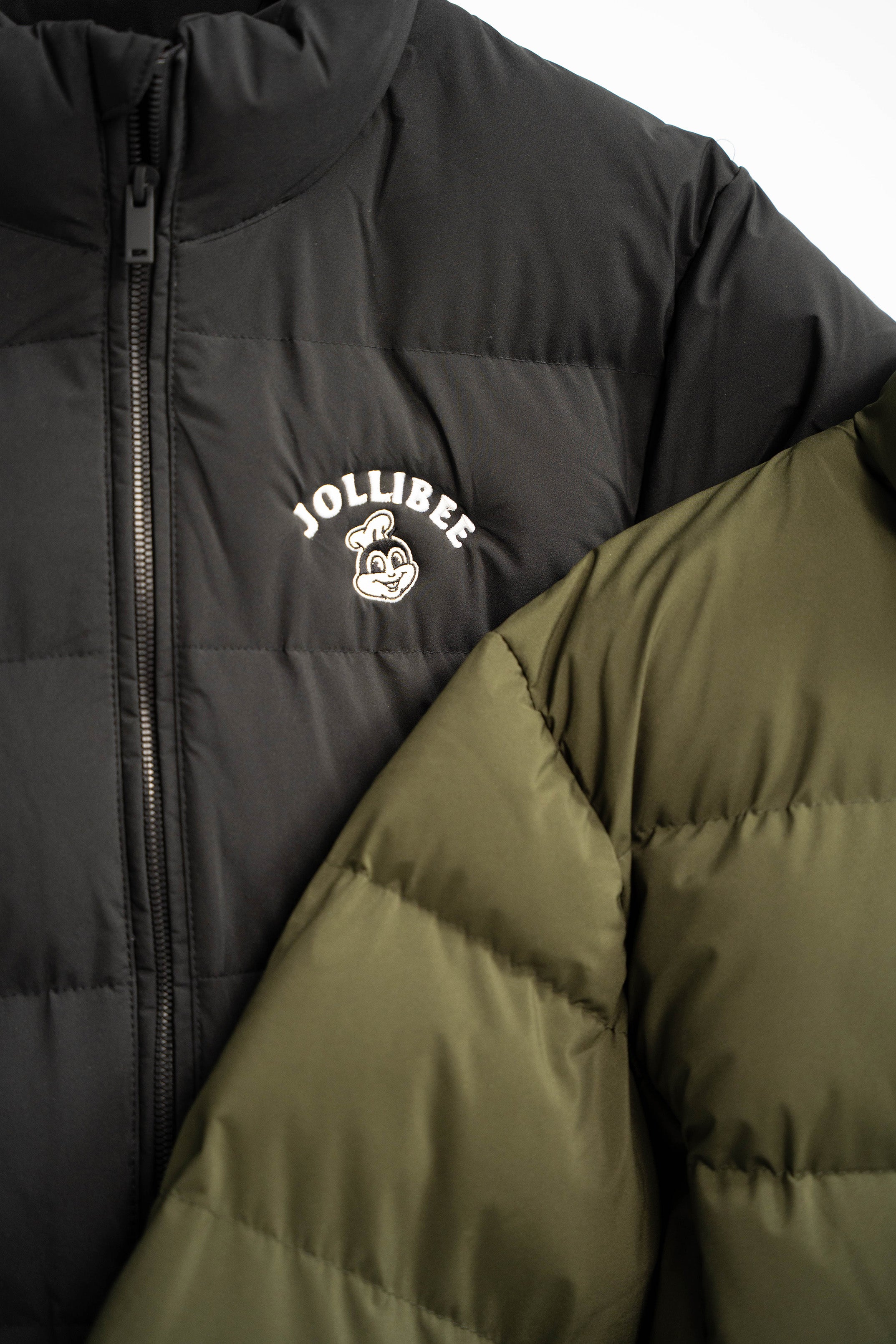 Two puffer jackets, one black with a logo and one green, on a white background.