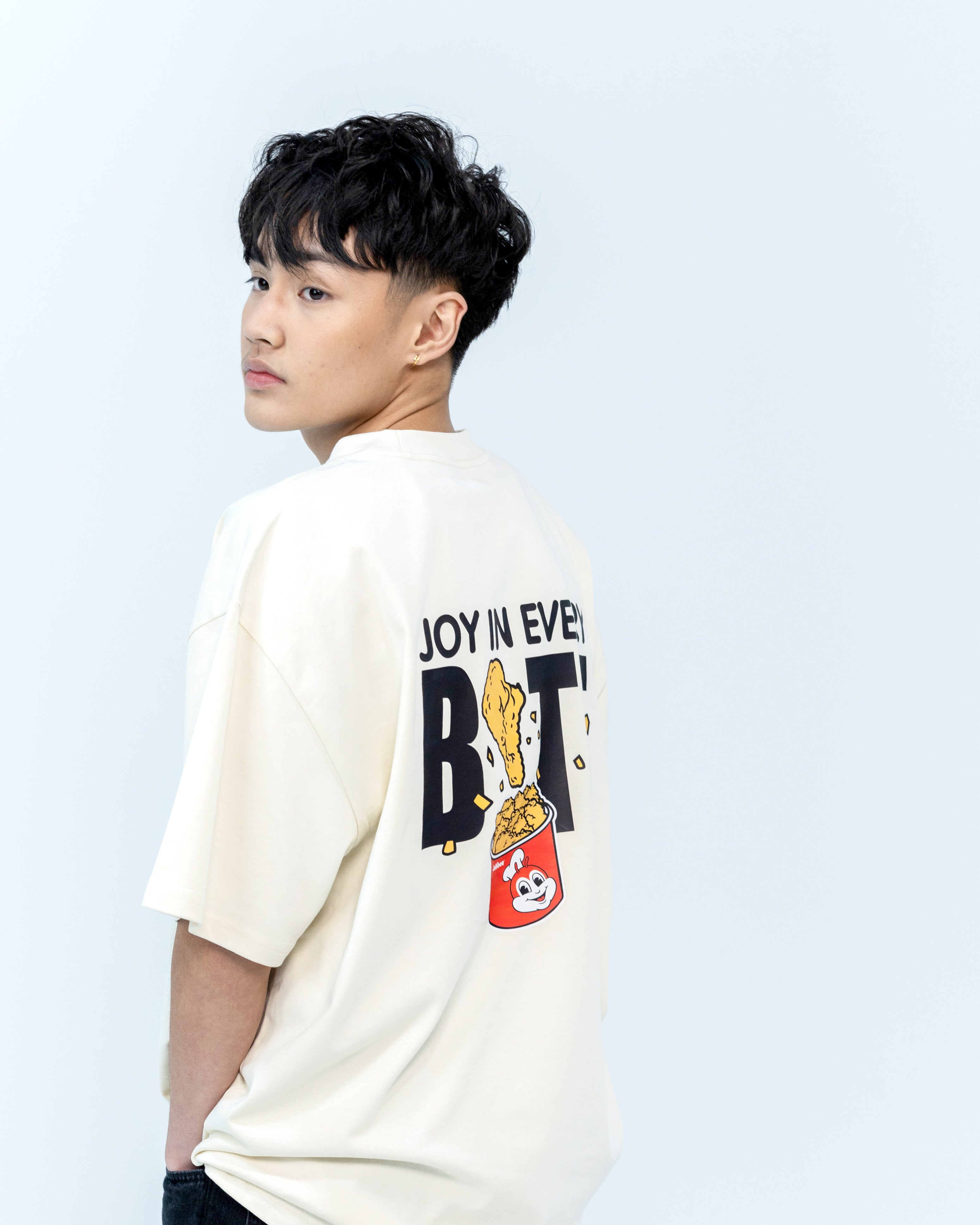 Guy wearing a cream colored tee with 'JOY IN EVERY BITE' on the back.