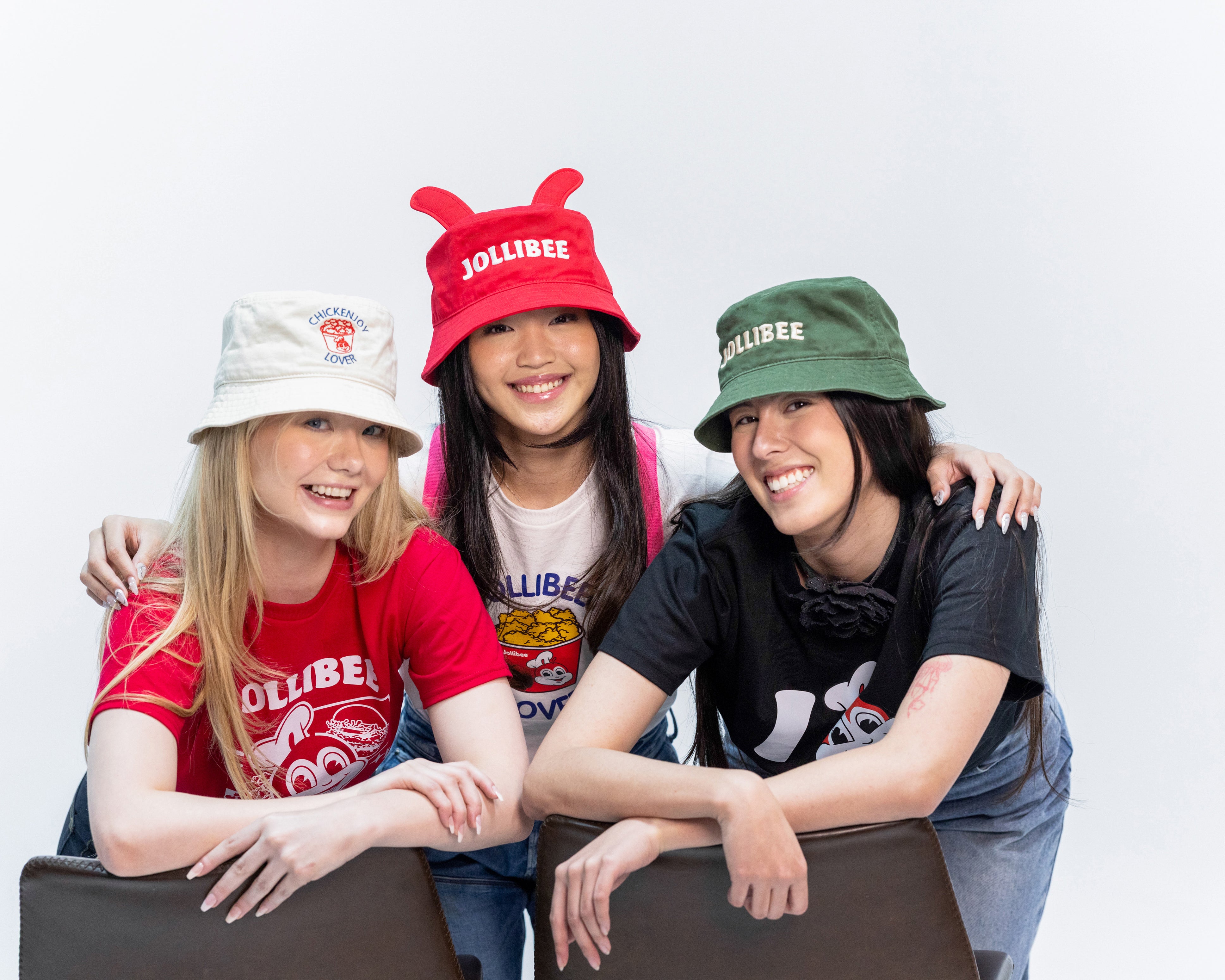 Three people wearing Jollibee branded hats and shirts against a white background
