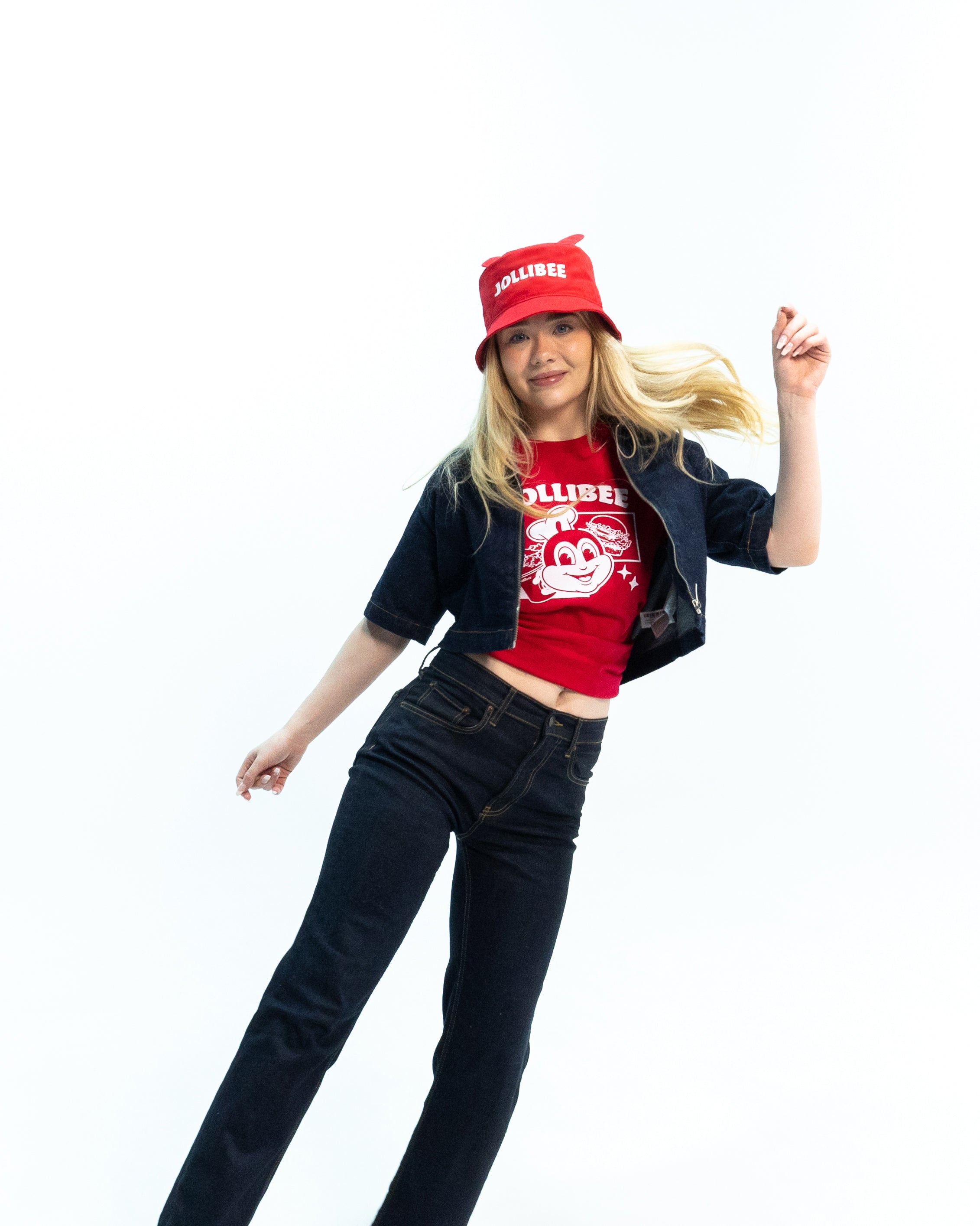 Person wearing a red cap and red t-shirt with a black jacket and jeans on a white background