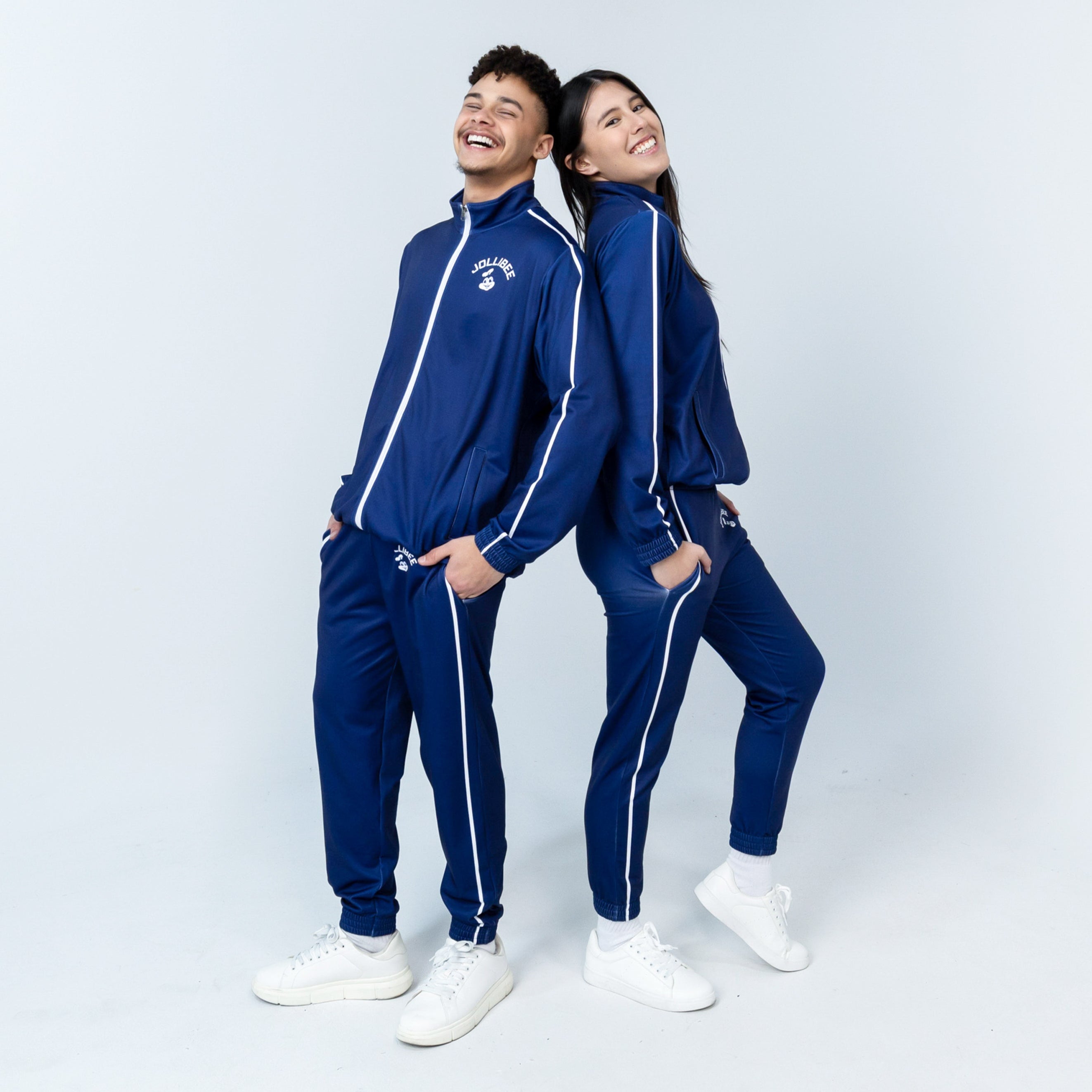 young man and young woman leaning on each other smiling and wearing Jollibee merch blue tracksuit