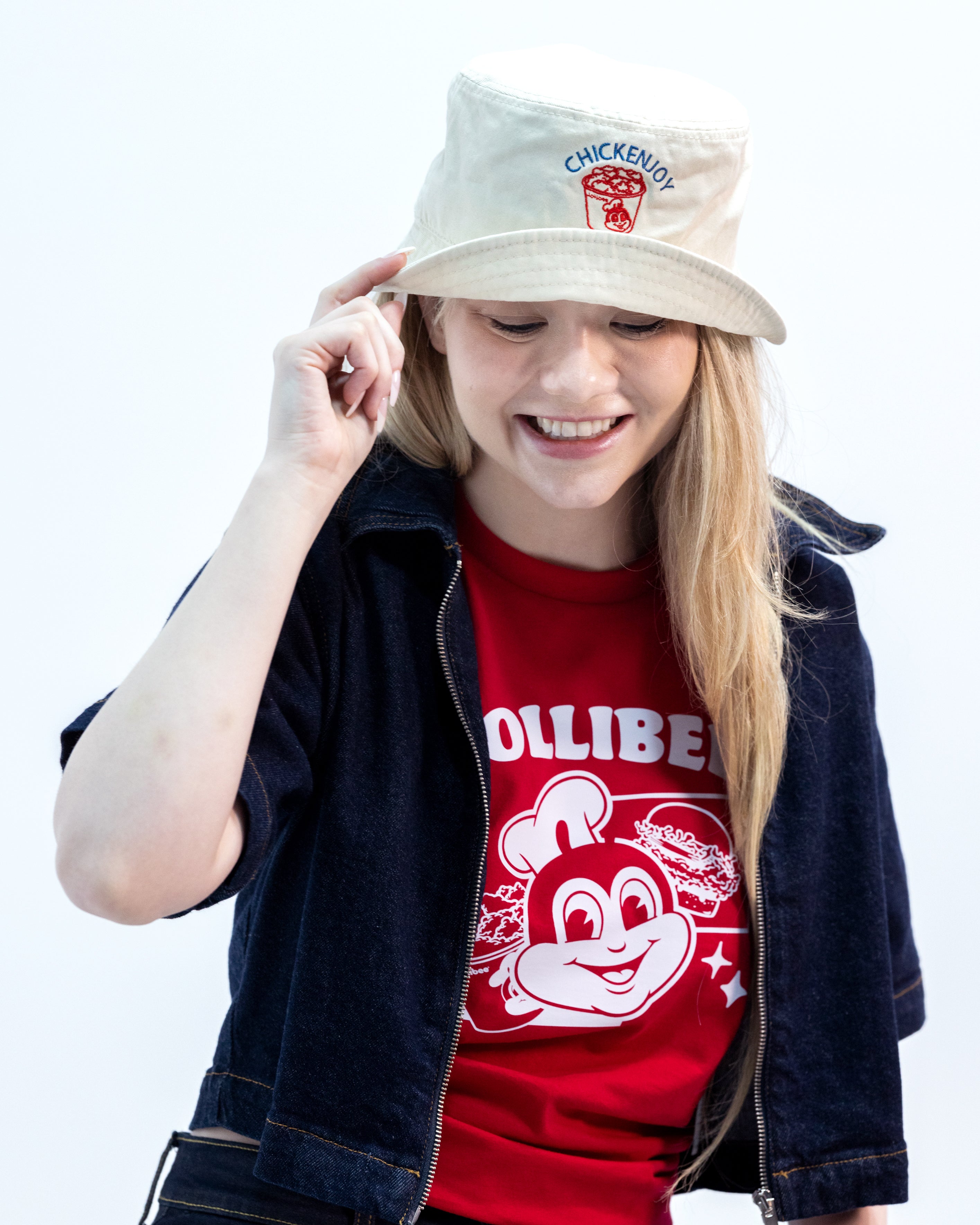 Person wearing a red t-shirt with a cartoon character and a beige bucket hat with branding.
