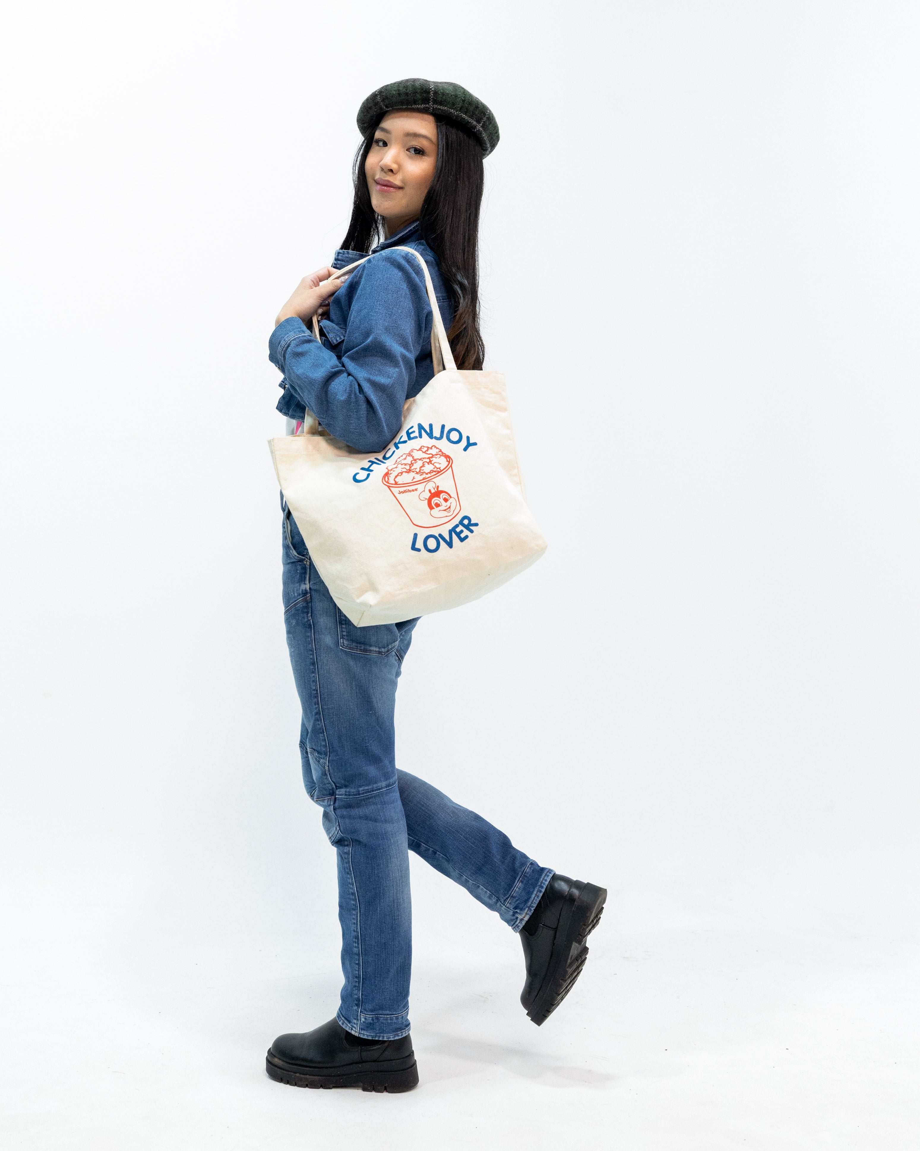 Person holding a tote bag with text and graphics 'CHICKENJOY LOVER' on a white background
