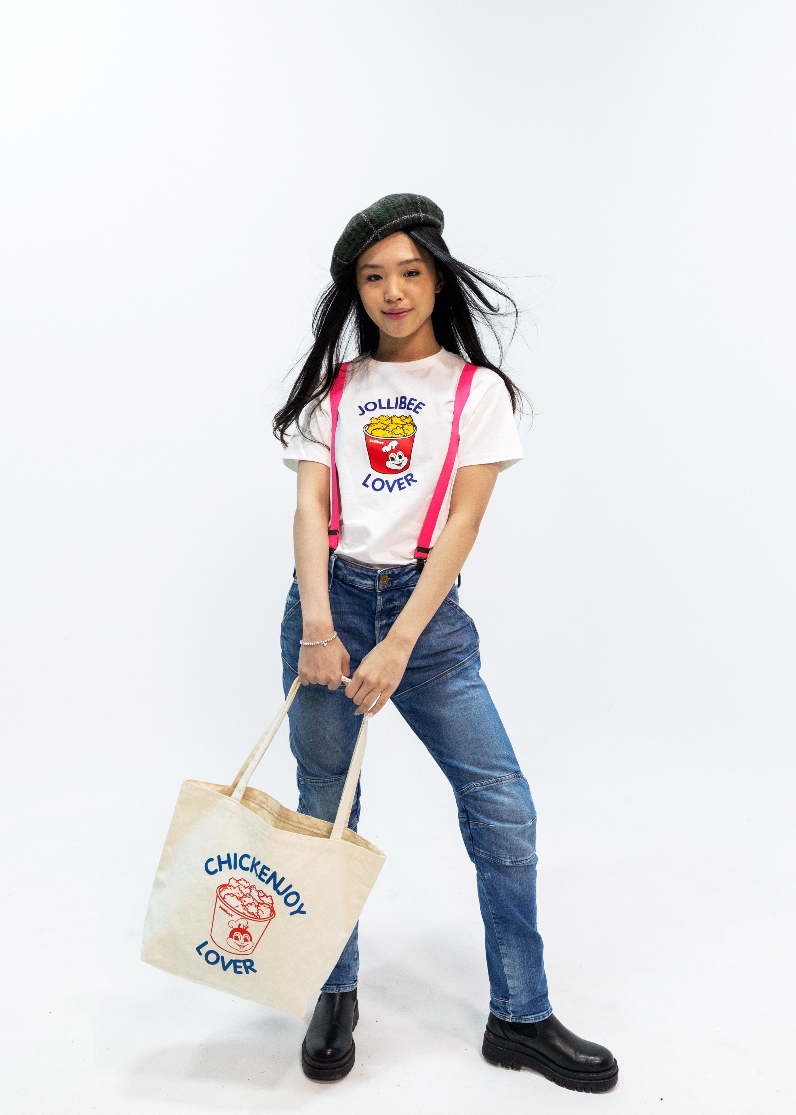 Person wearing a 'Chickenjoy Lover' t-shirt and holding a matching tote bag on a white background