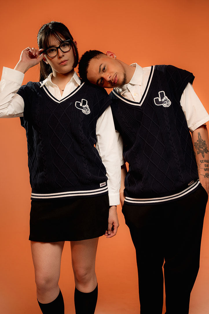 Two people wearing matching navy blue vests over white shirts with a logo on an orange background.