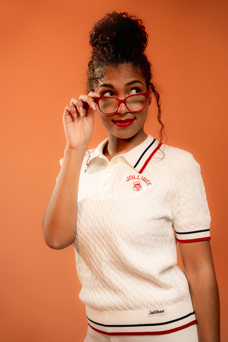 Woman wearing a white polo shirt with a Jollibee brand logo against an orange background