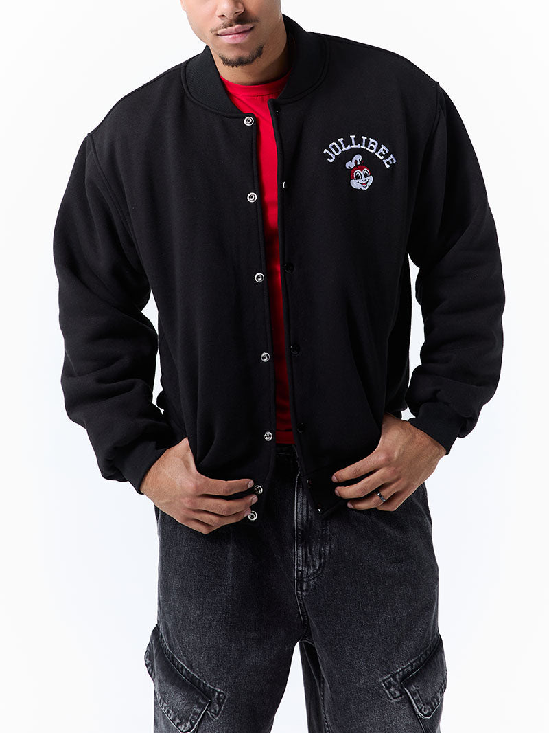 Person wearing a black letterman jacket with a red shirt underneath on a white background