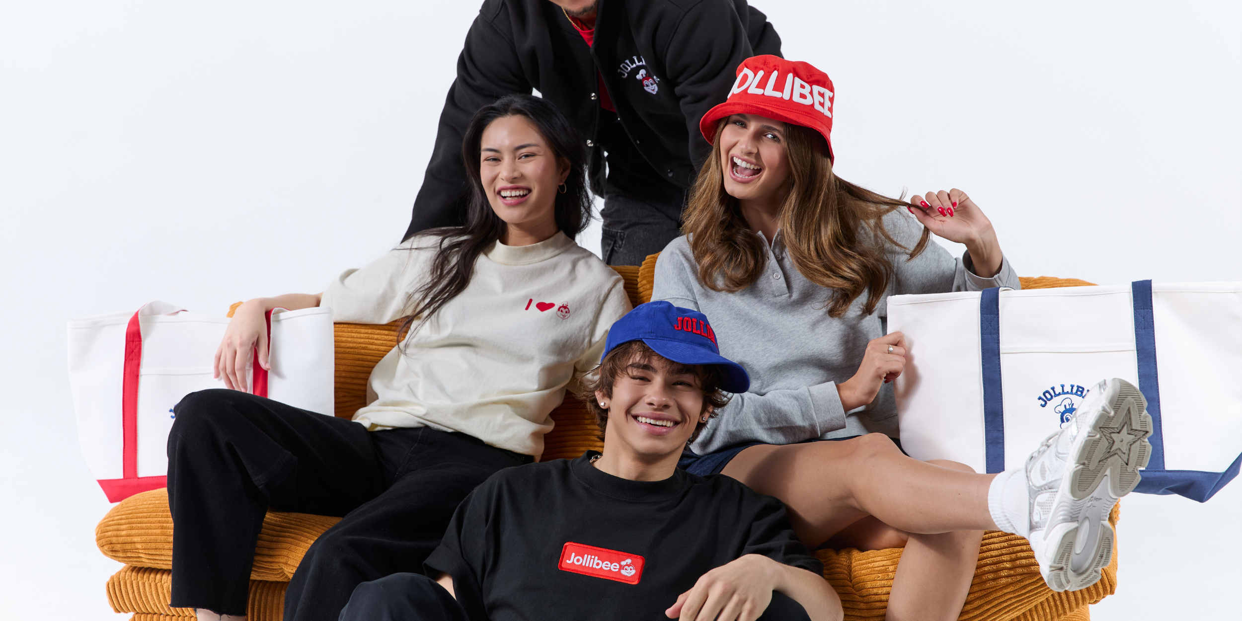 Three people sitting on a couch with 'JOLLIBEE' branding, including clothing and a bag.