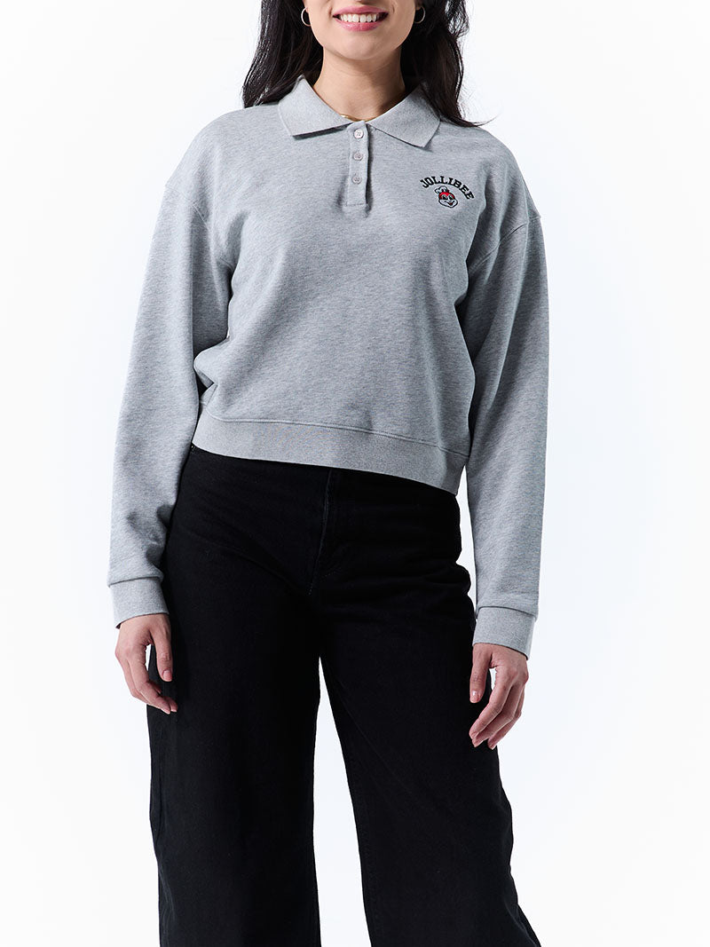 Person wearing a gray long-sleeve polo sweatshirt with a logo on a white background
