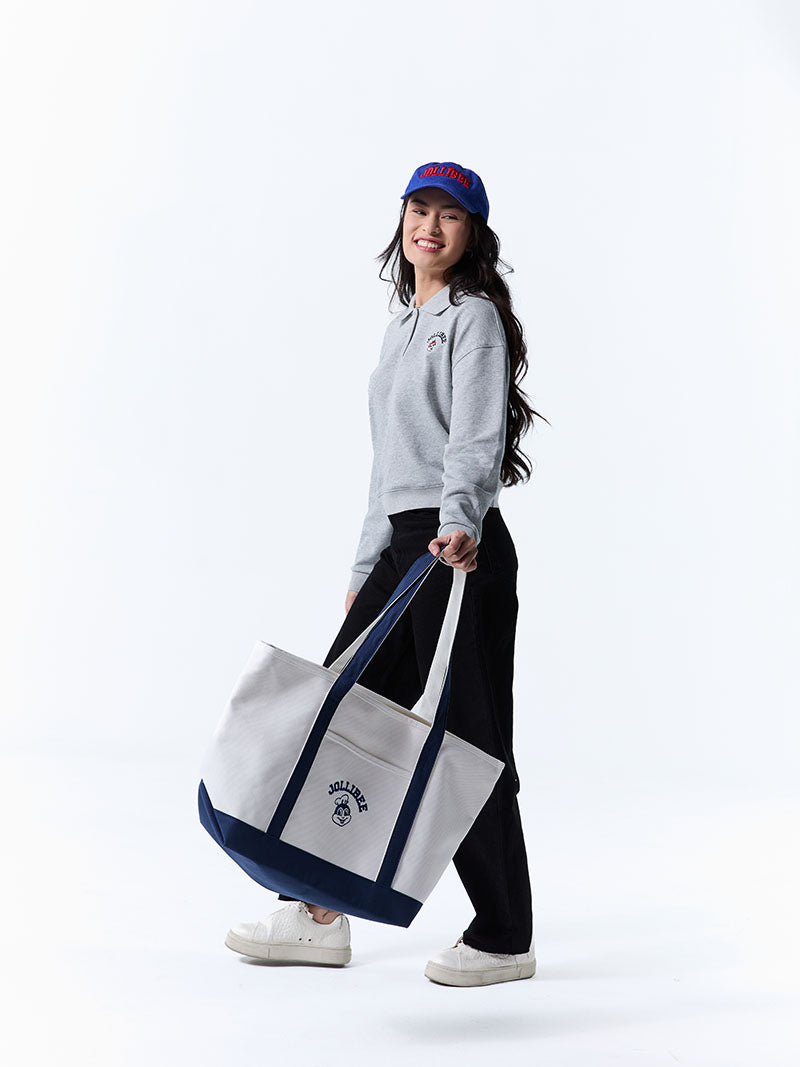 Person holding a large white tote bag with blue accents on a white background
