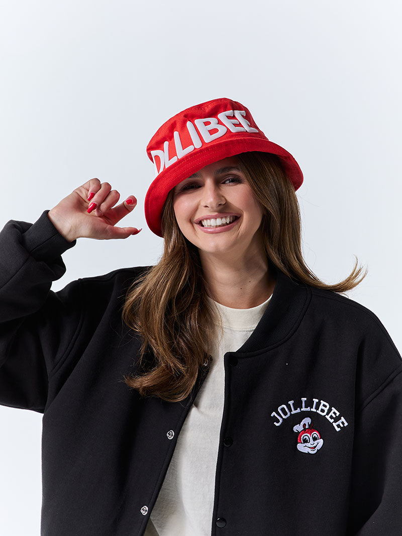 Person wearing a red Jollibee bucket hat and black jacket with Jollibee logo on a white background.