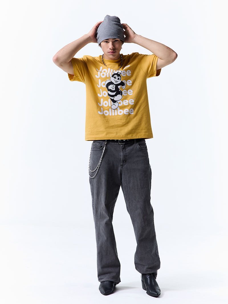 Person wearing a yellow t-shirt with a Jollibee logo design and text, dark jeans, and a gray beanie on a white background