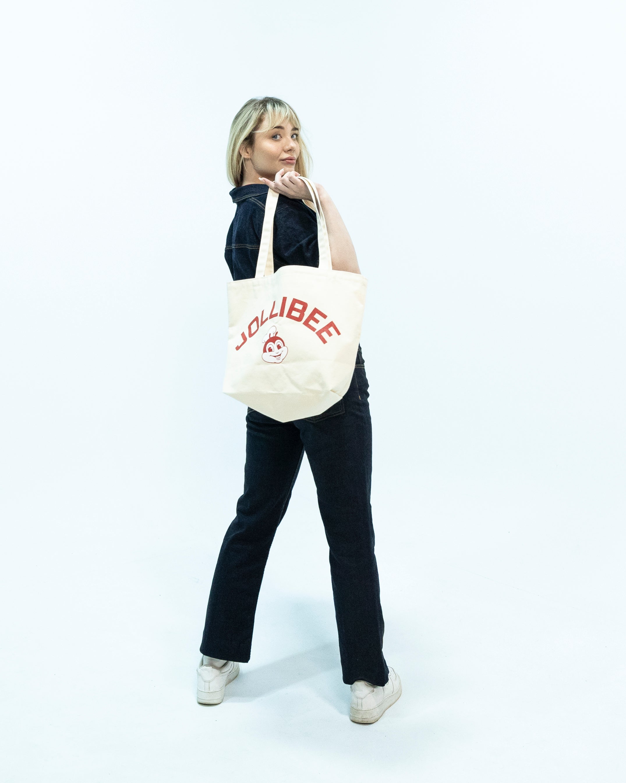 Young woman holding a Jollibee tote bag against a white background