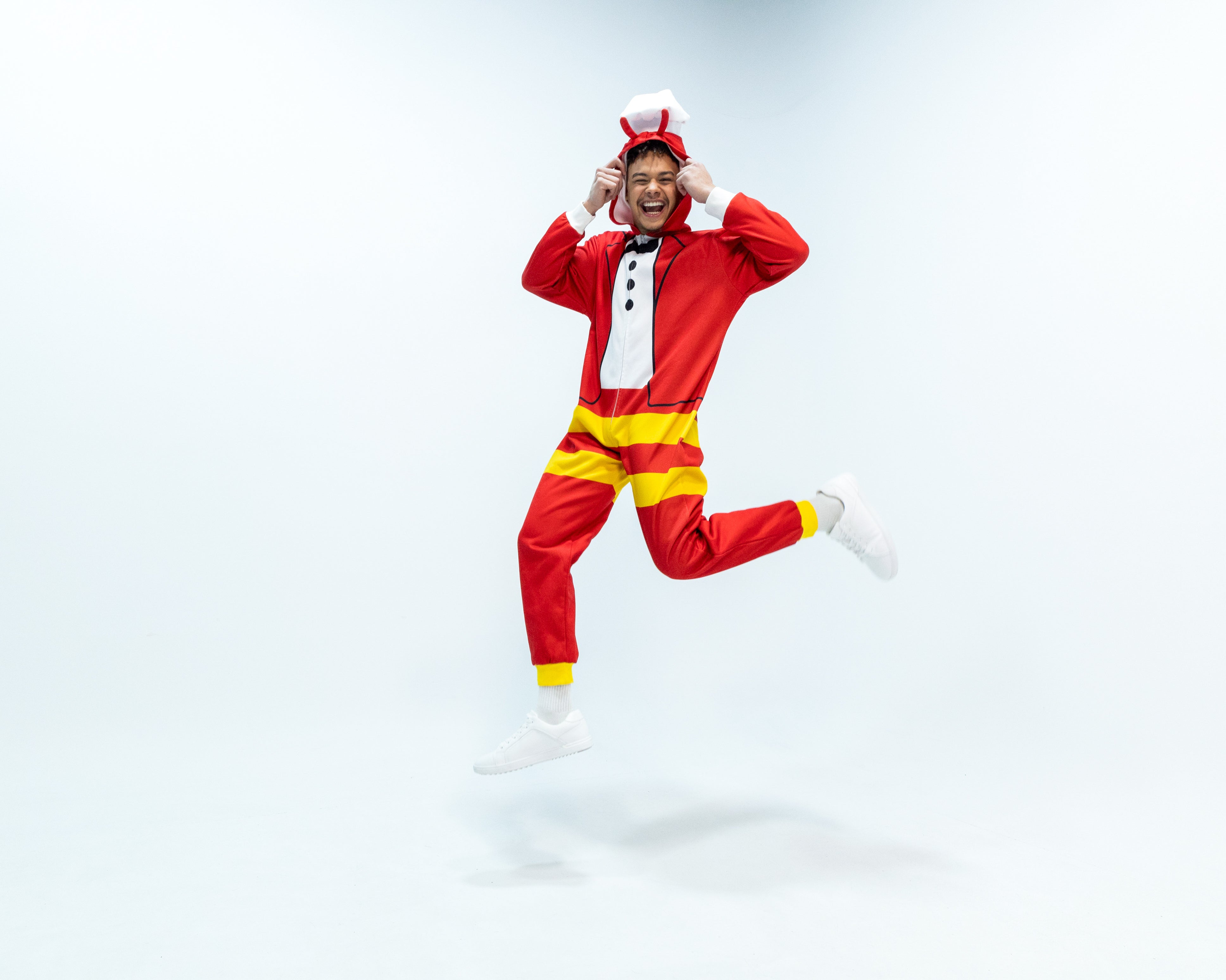 Person wearing a Jollibee red and yellow onesie on a white background