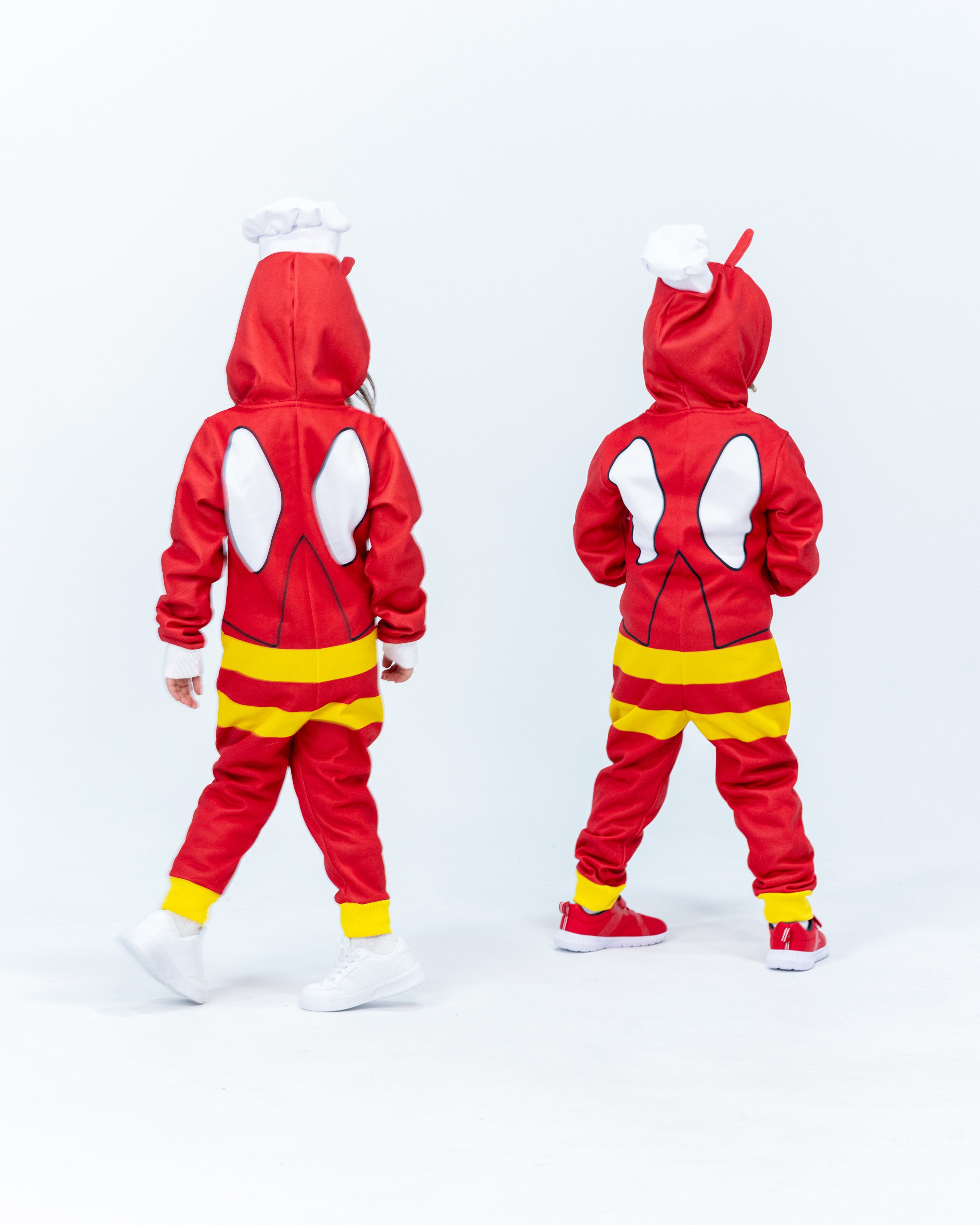 Two children wearing Jollibee red and yellow onesies on a white background