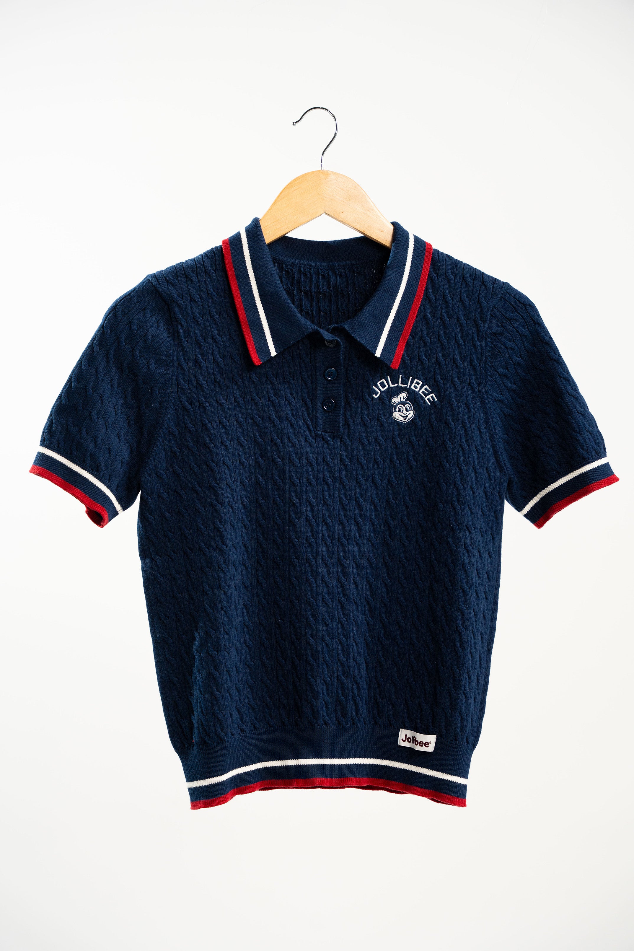 Navy blue polo shirt with white and red accents on a wooden hanger against a white background