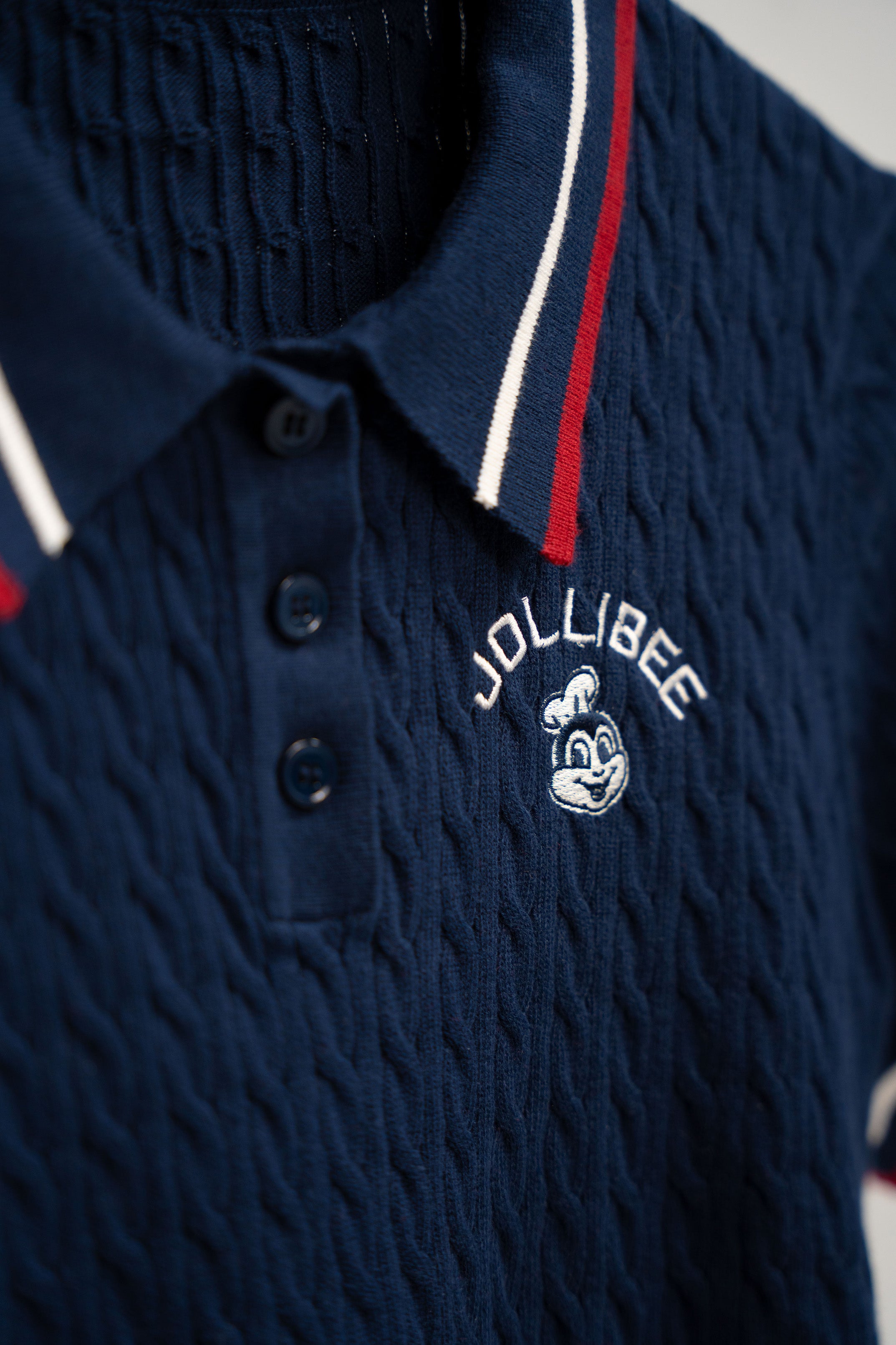 Navy blue textured polo shirt with Jollibee logo on a gray background