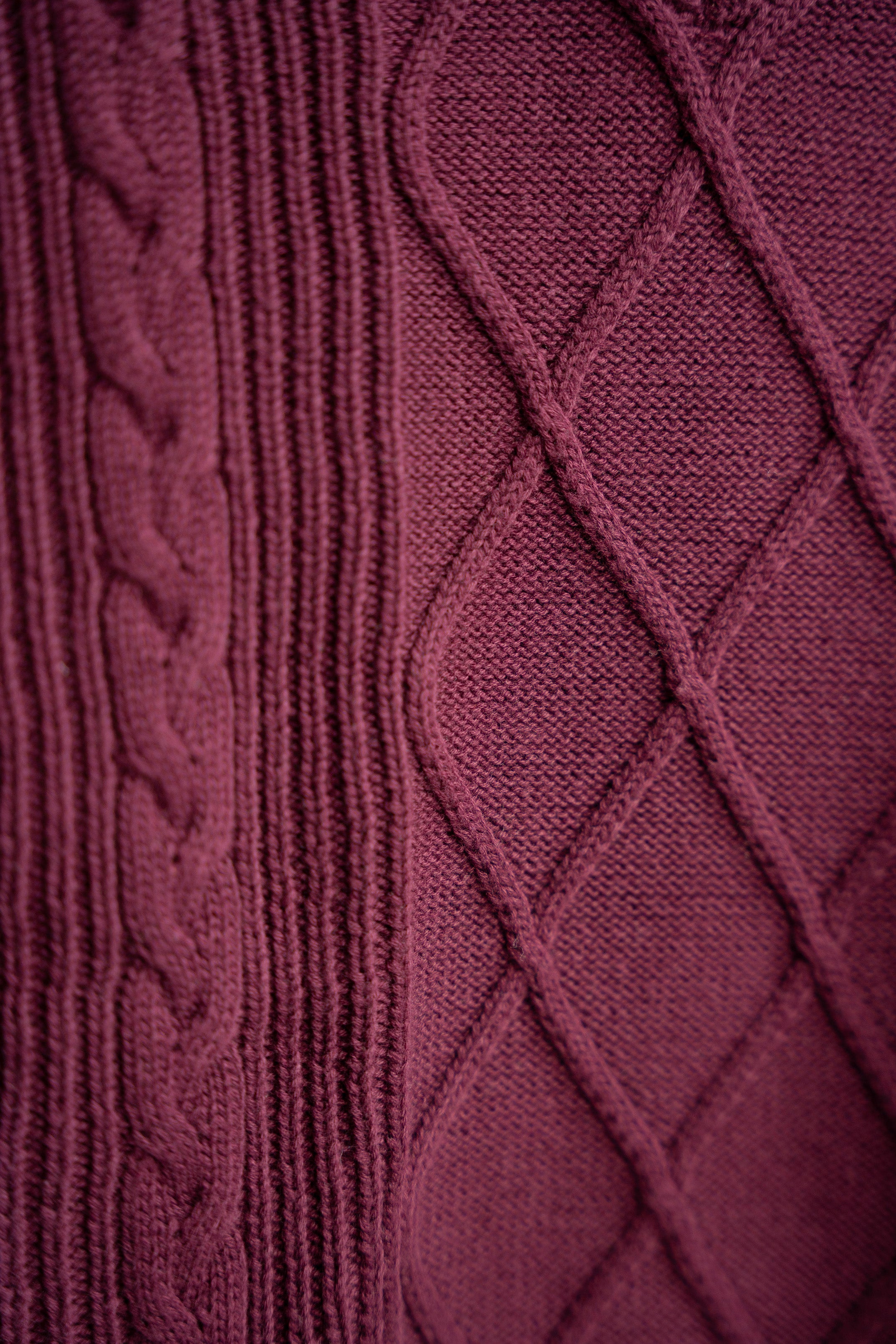 Close-up of a maroon knitted fabric with cable pattern