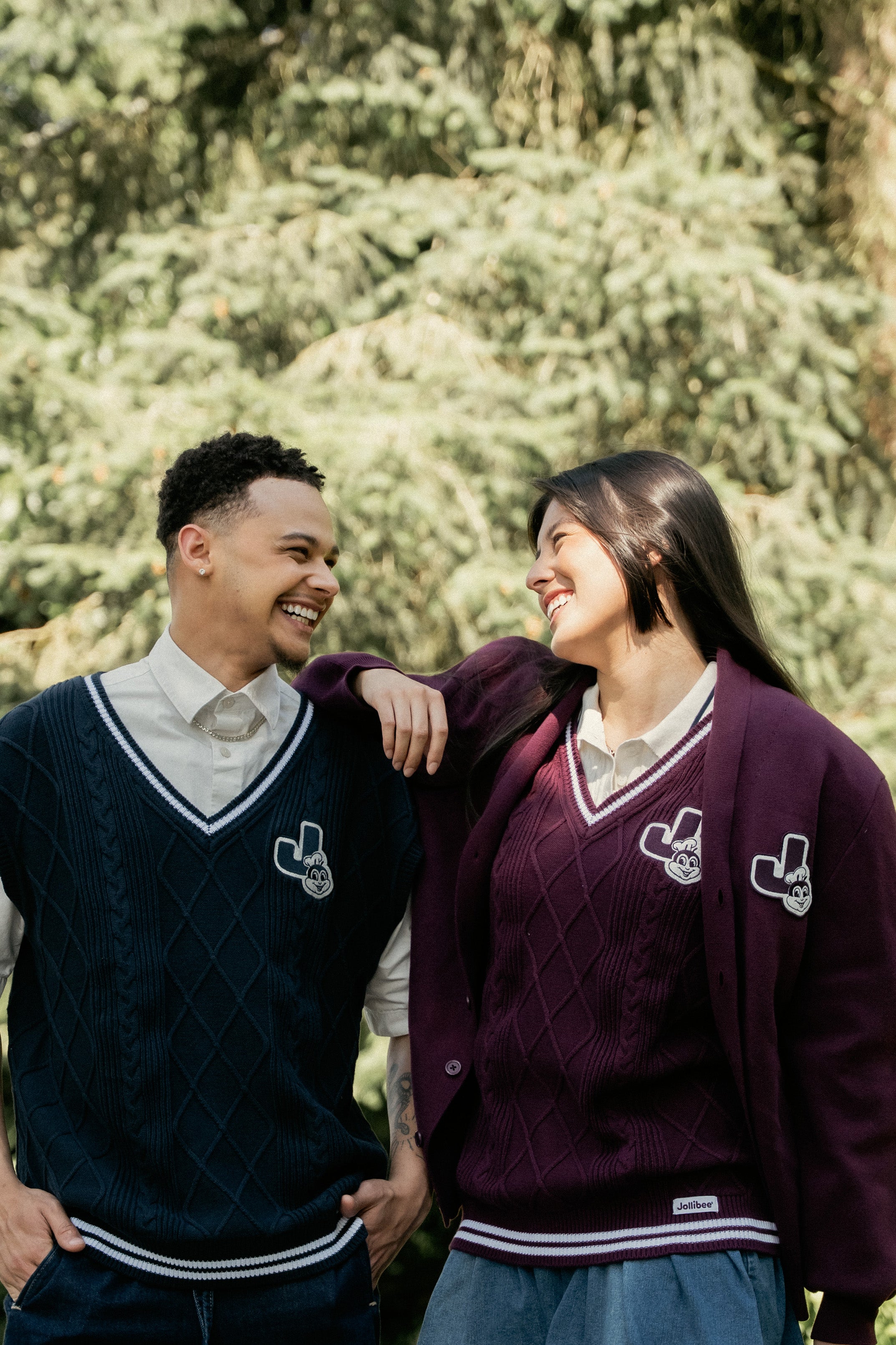 Two people in matching Jollibee merch standing outdoors with trees in the background