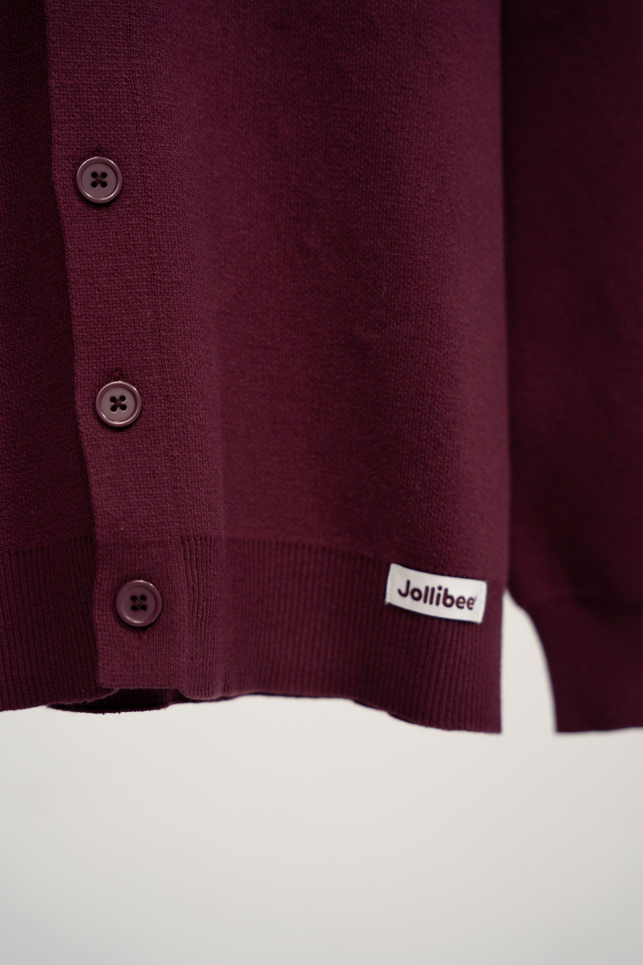 Maroon cardigan with button details and a visible brand logo on a white background