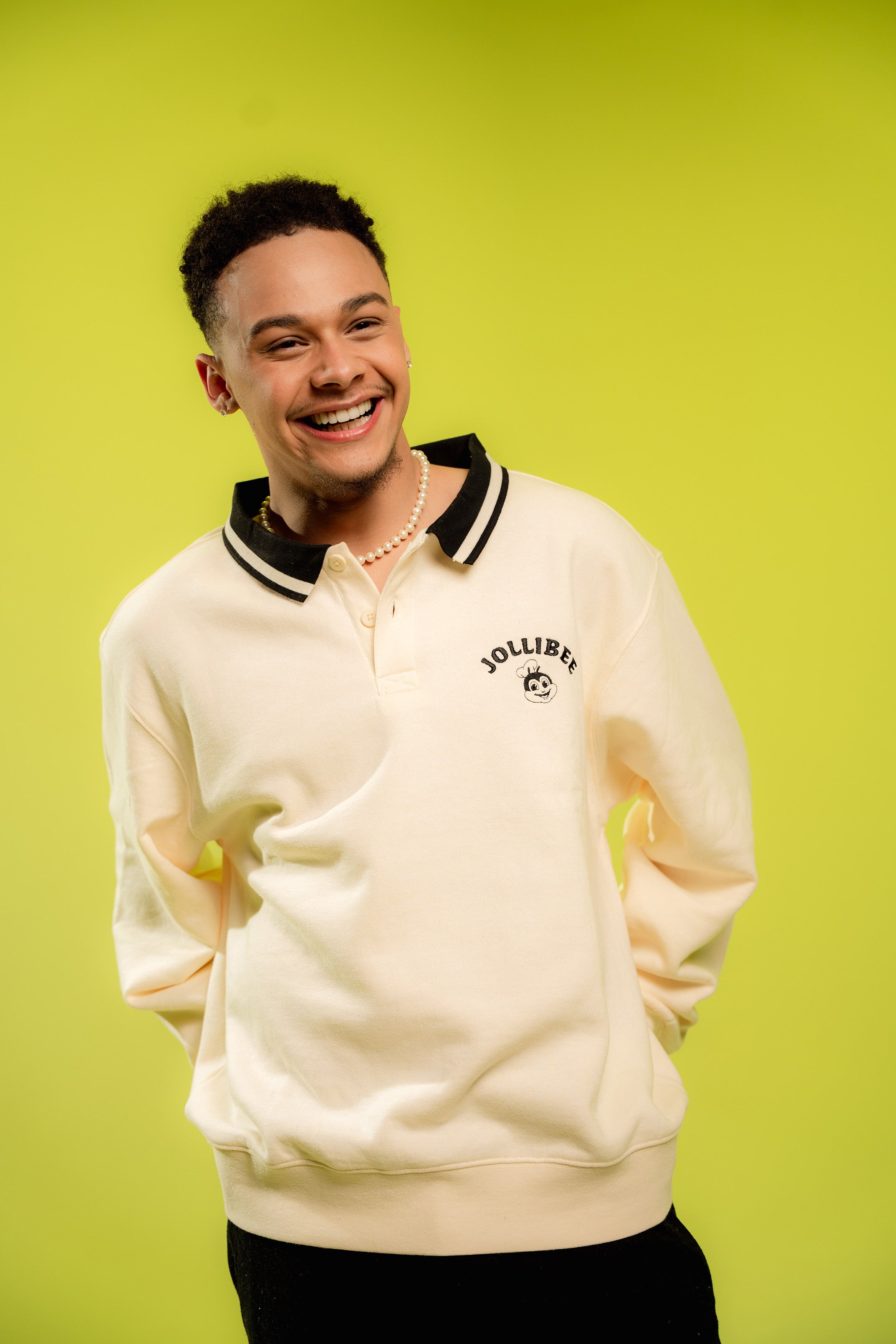 Person wearing a cream-colored sweatshirt with a brand logo on a bright green background