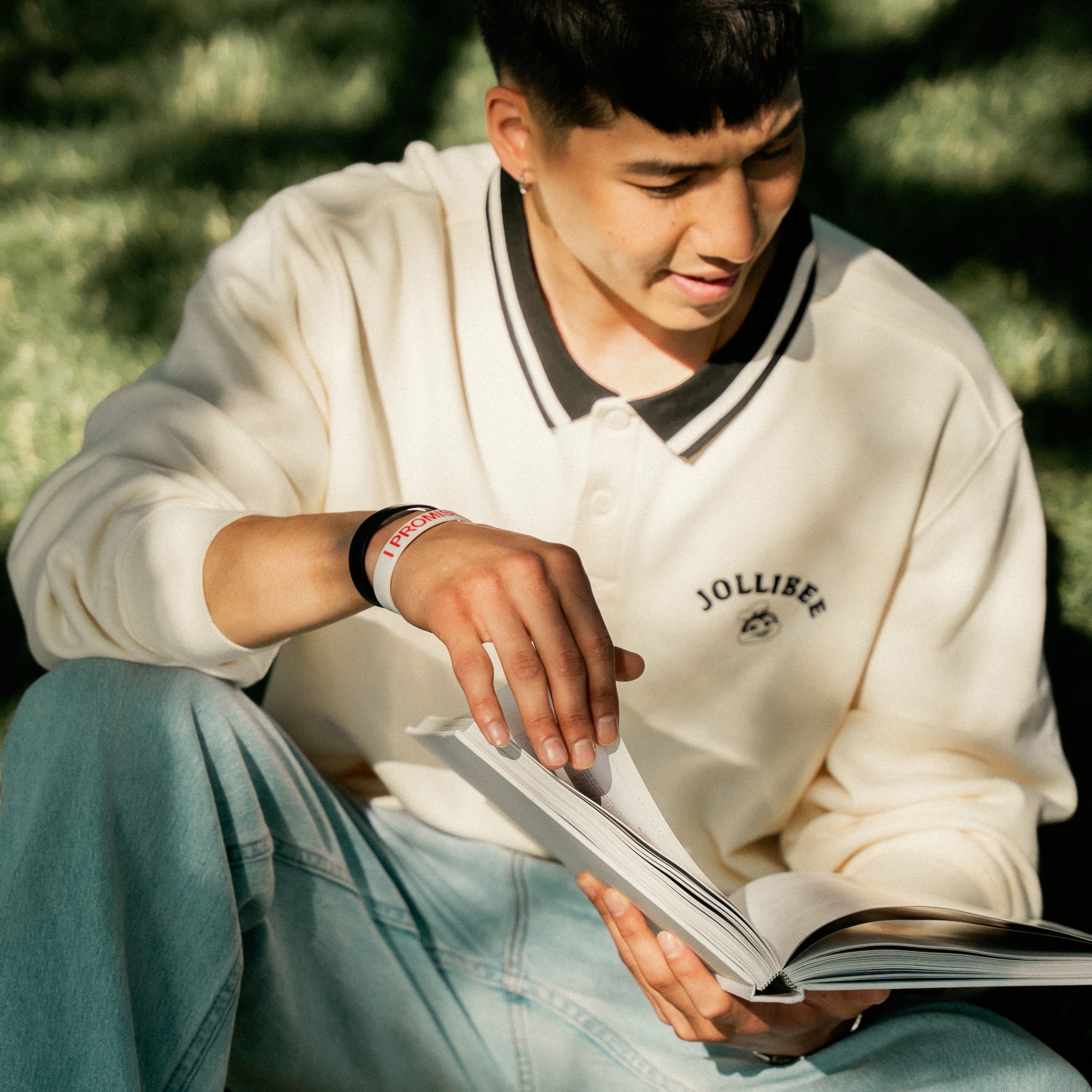 Person reading a book outdoors with a blurred natural background