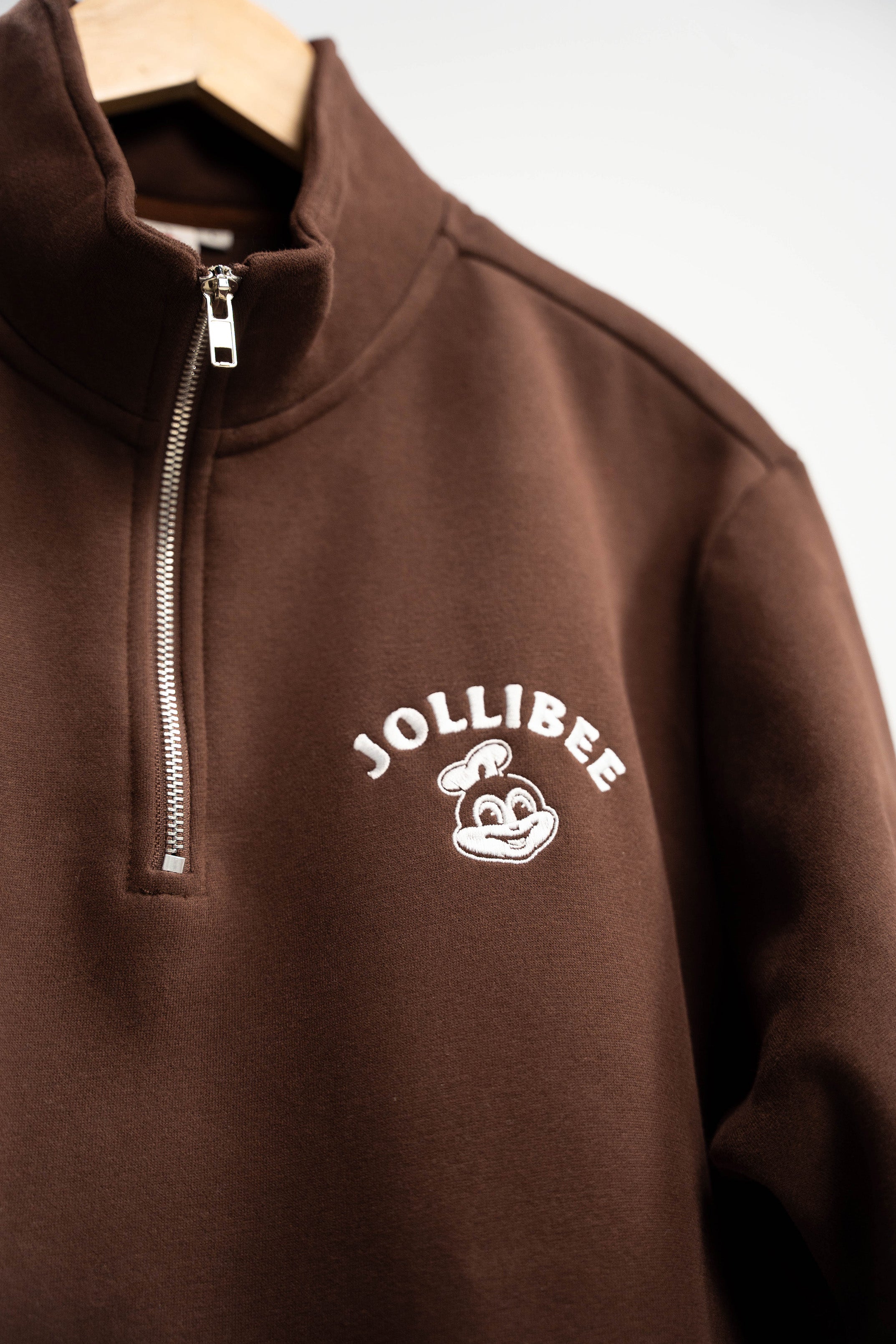 Brown half-zip sweatshirt with Jollibee logo on a white background
