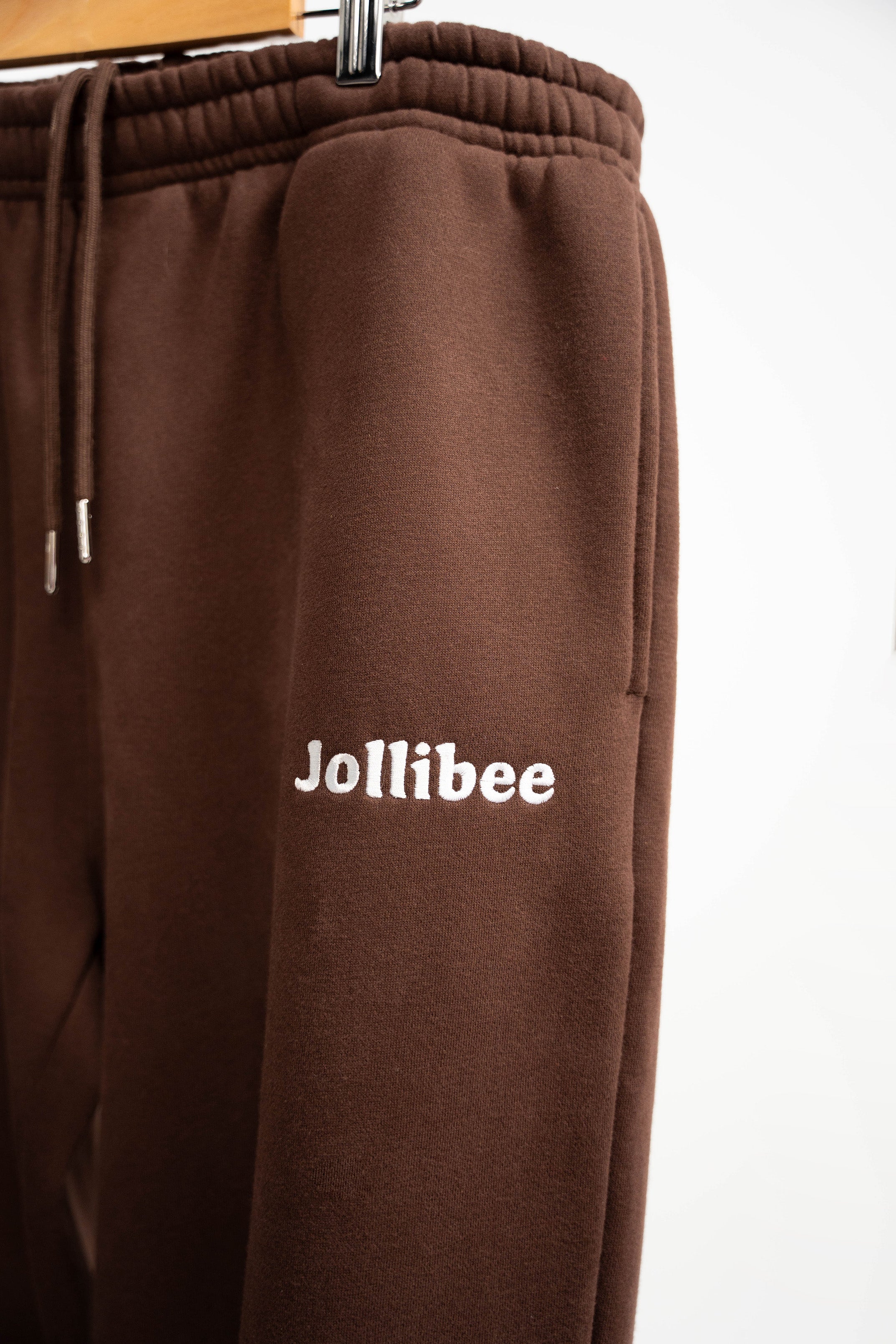 Brown sweatpants with 'Jollibee' logo on a white background