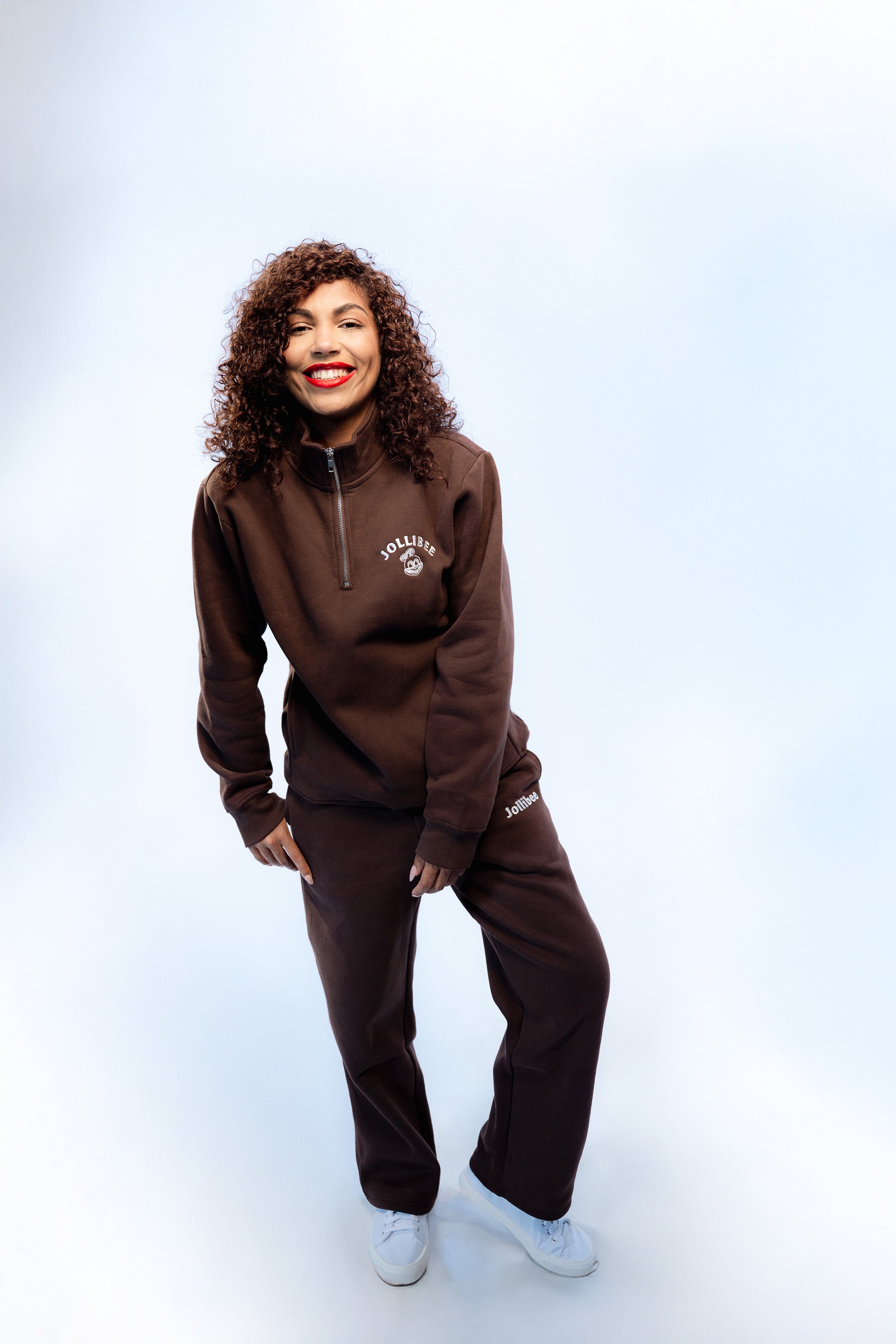 Person wearing a brown tracksuit with a logo on a white background