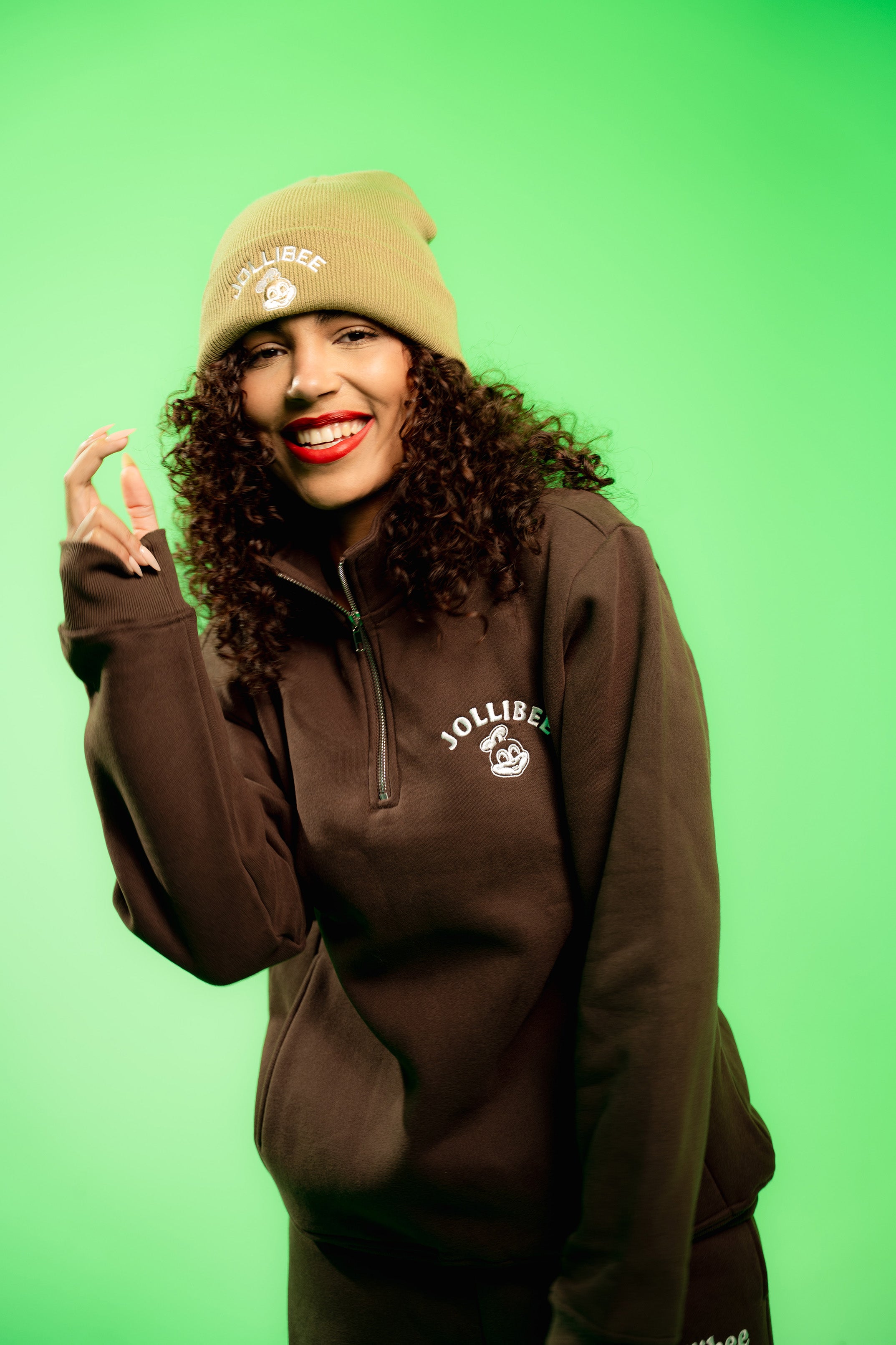 Person wearing a brown sweatshirt with a logo on a green background
