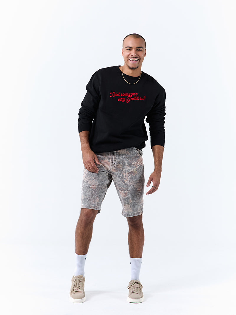 A young man wearing a black crewneck sweatshirt with a 'Did someone say Jollibee?' text across the chest on a white background.
