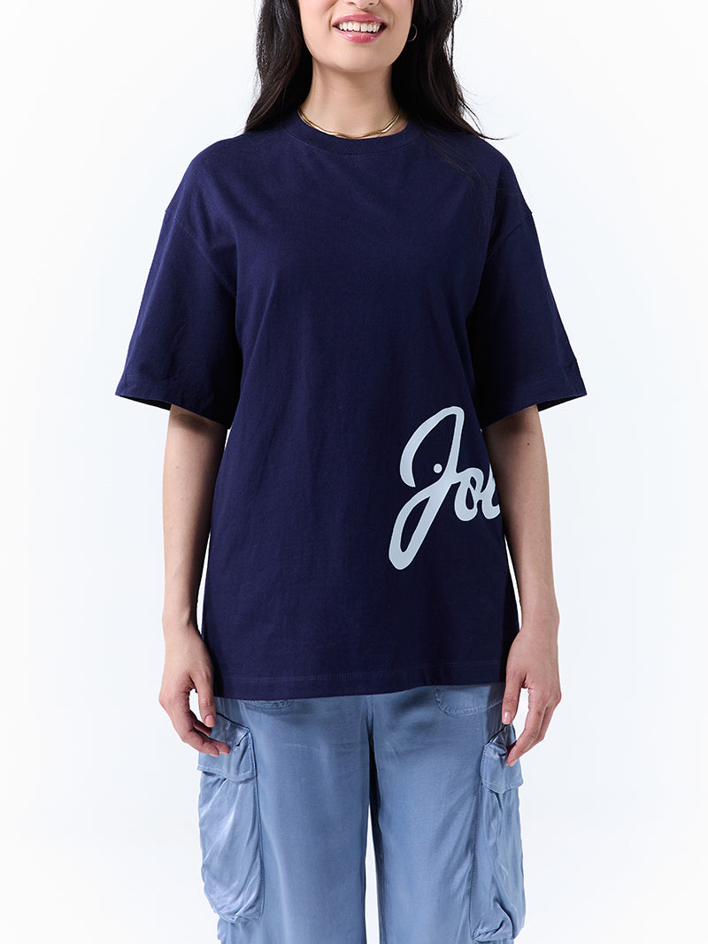 A young woman wearing a navy t-shirt with 'Jollibee' in script on the side on a white background.
