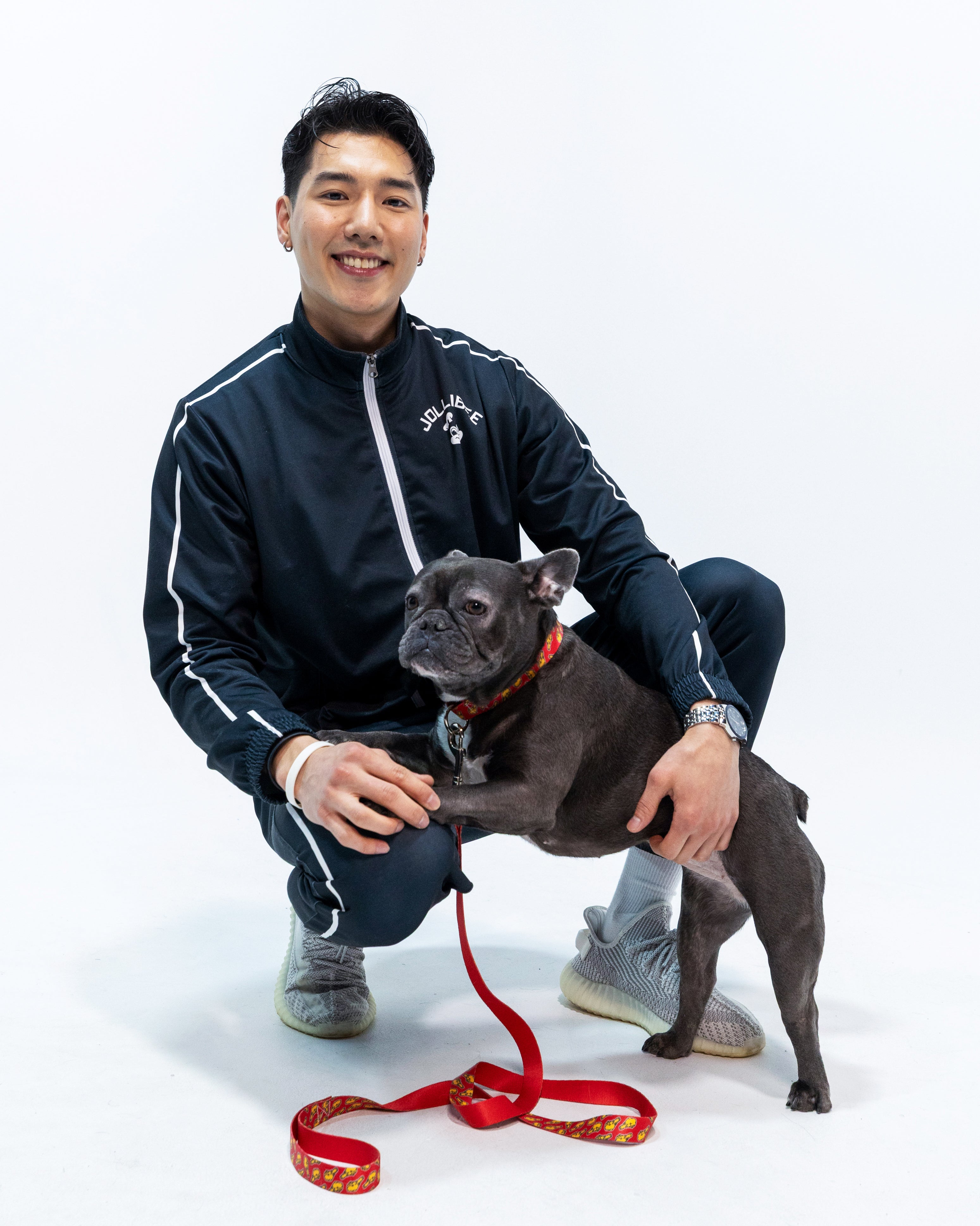 guy wearing Jollibee merch black tracksuit with his dog on Jollibee leash and collar