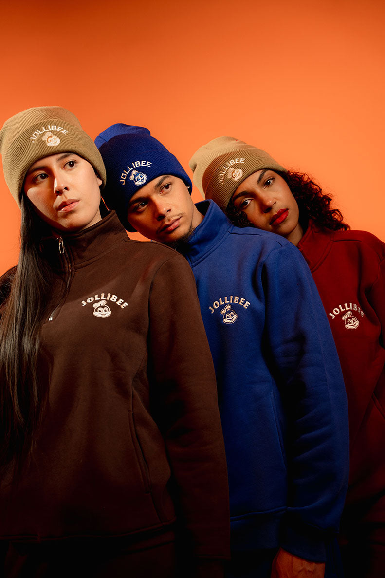 Three people wearing branded beanies and sweatshirts against an orange background