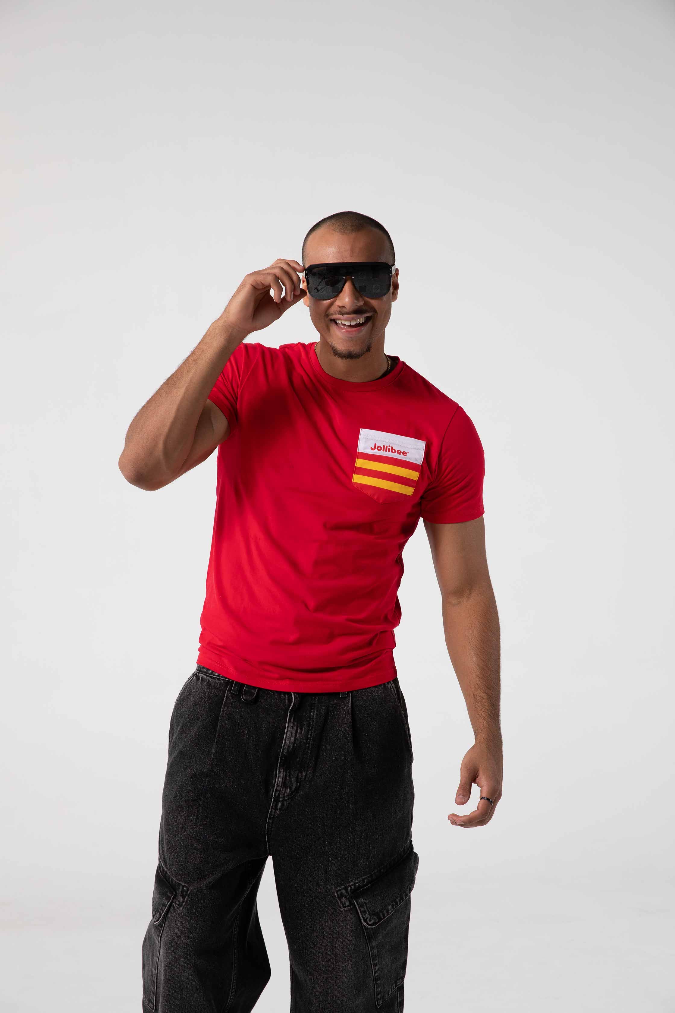 Man wearing a red t-shirt with a Jollibee logo and sunglasses, standing against a white background
