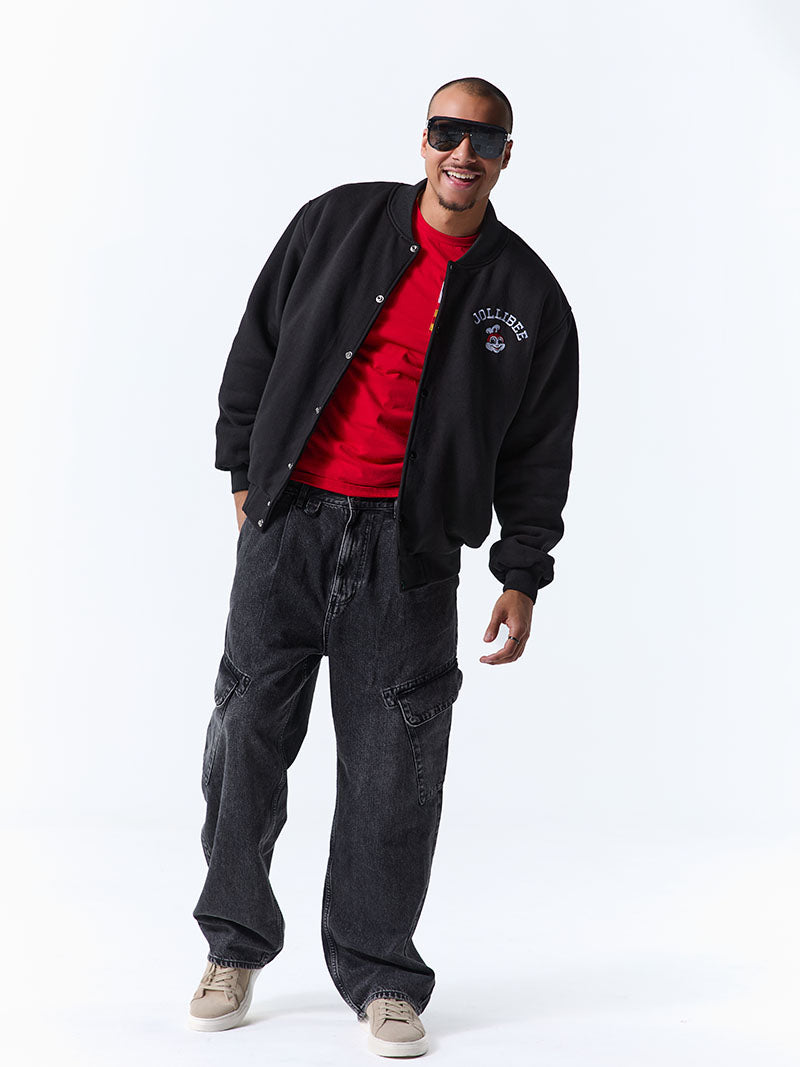 Man wearing a black jacket, red shirt, and dark pants on a white background