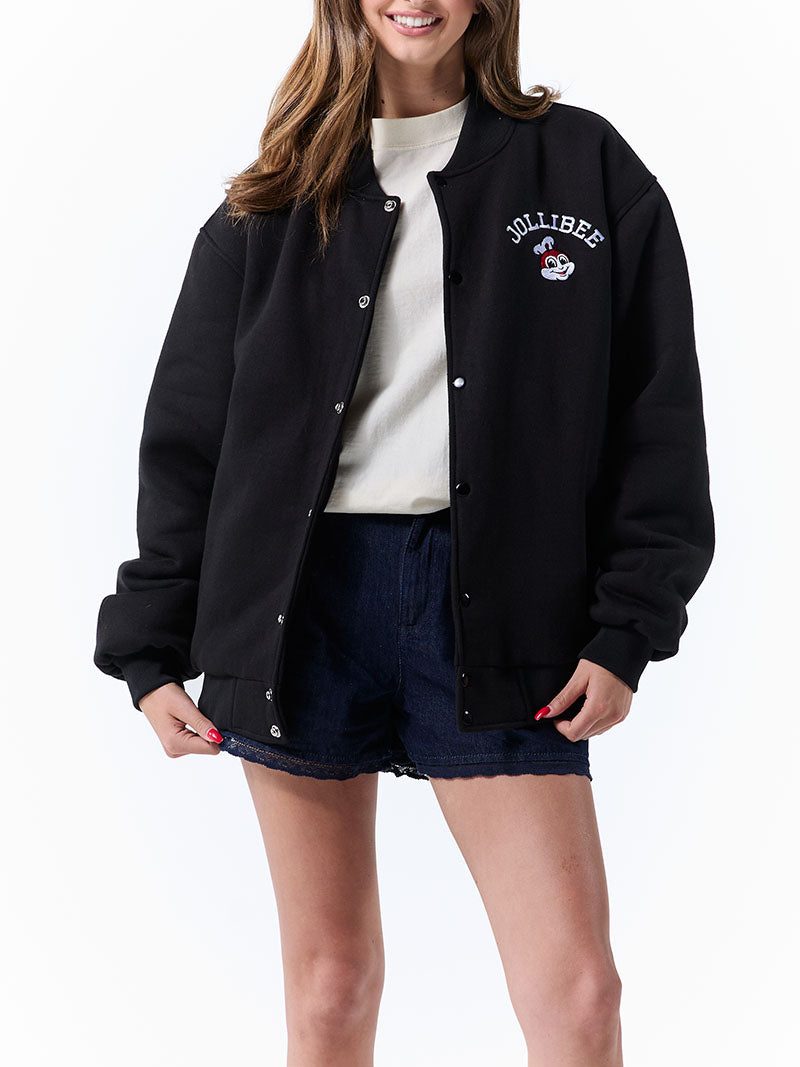 Person wearing a black varsity jacket with 'JOLLIBEE' branding on a white background