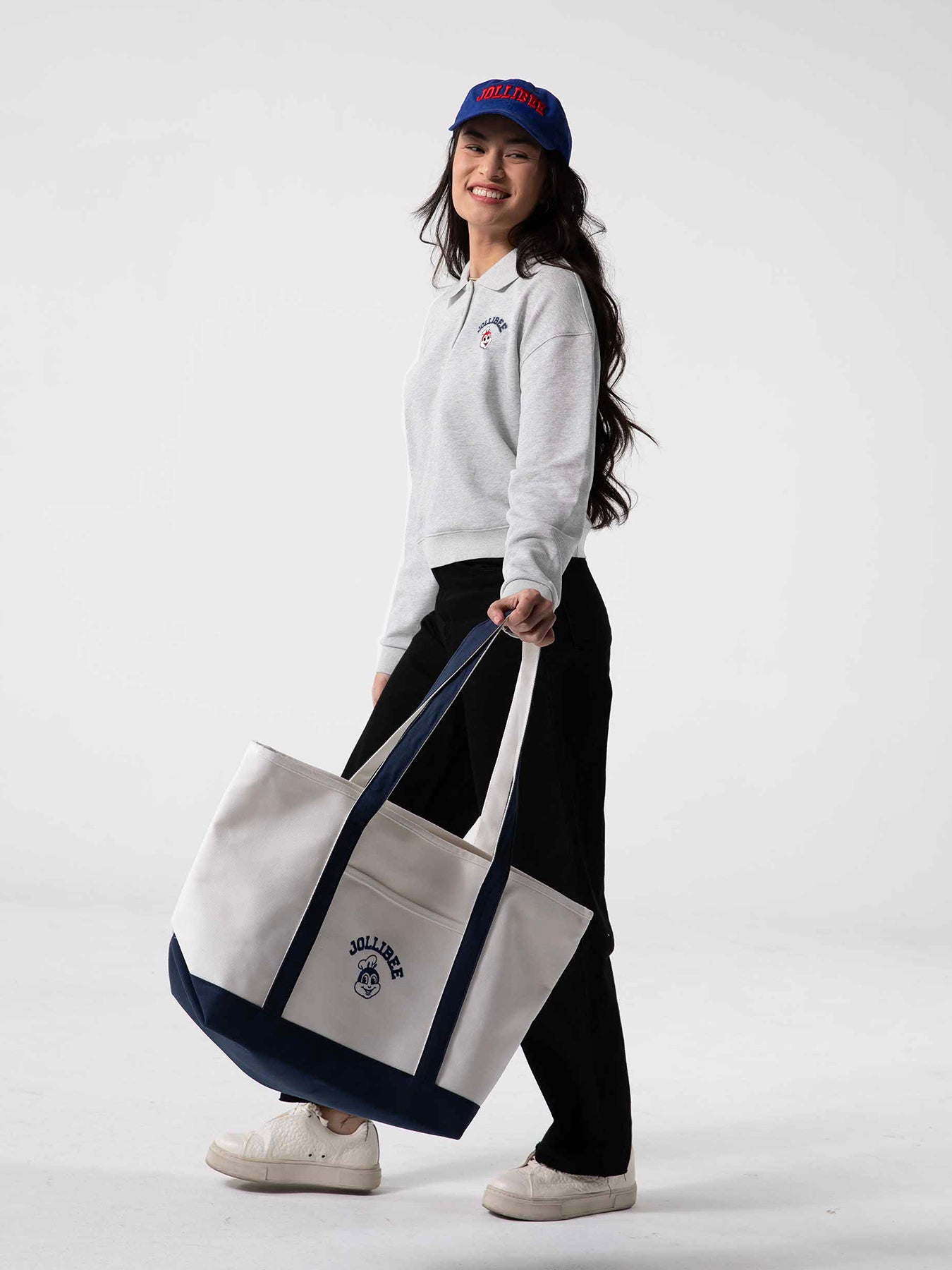 Person holding a large tote bag with a visible Jollibee logo on a white background