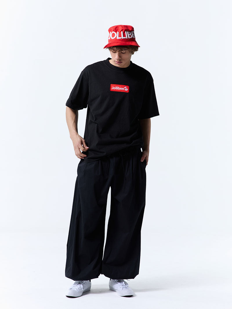 Person wearing a black t-shirt with a red logo and a red cap on a white background