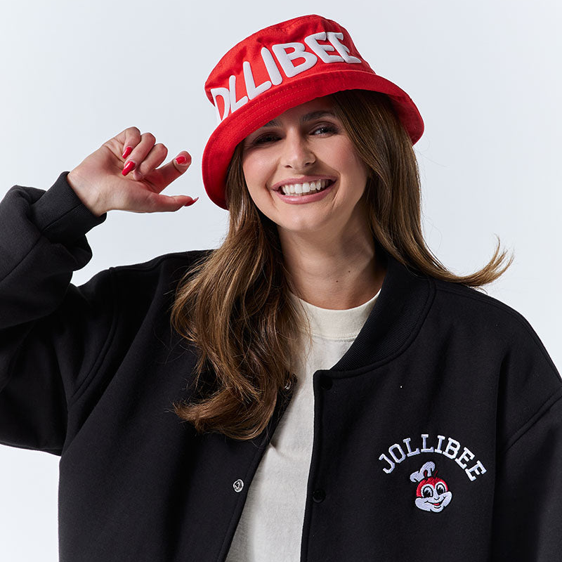 Person wearing a red Jollibee hat and black jacket with Jollibee logo on a white background