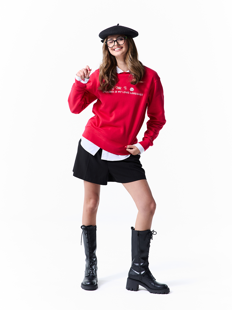 Person wearing a red sweatshirt with text, black shorts, black boots, and a black beret on a white background