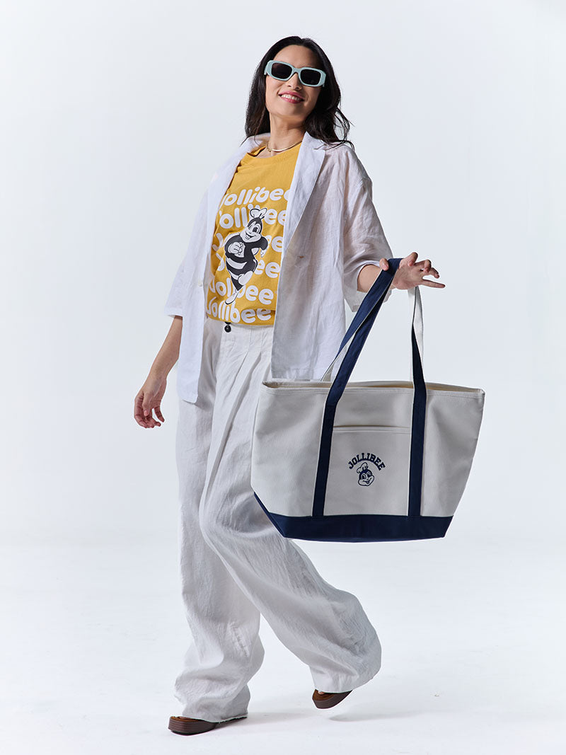 Person holding a tote bag with a visible Jollibee brand logo on a white background