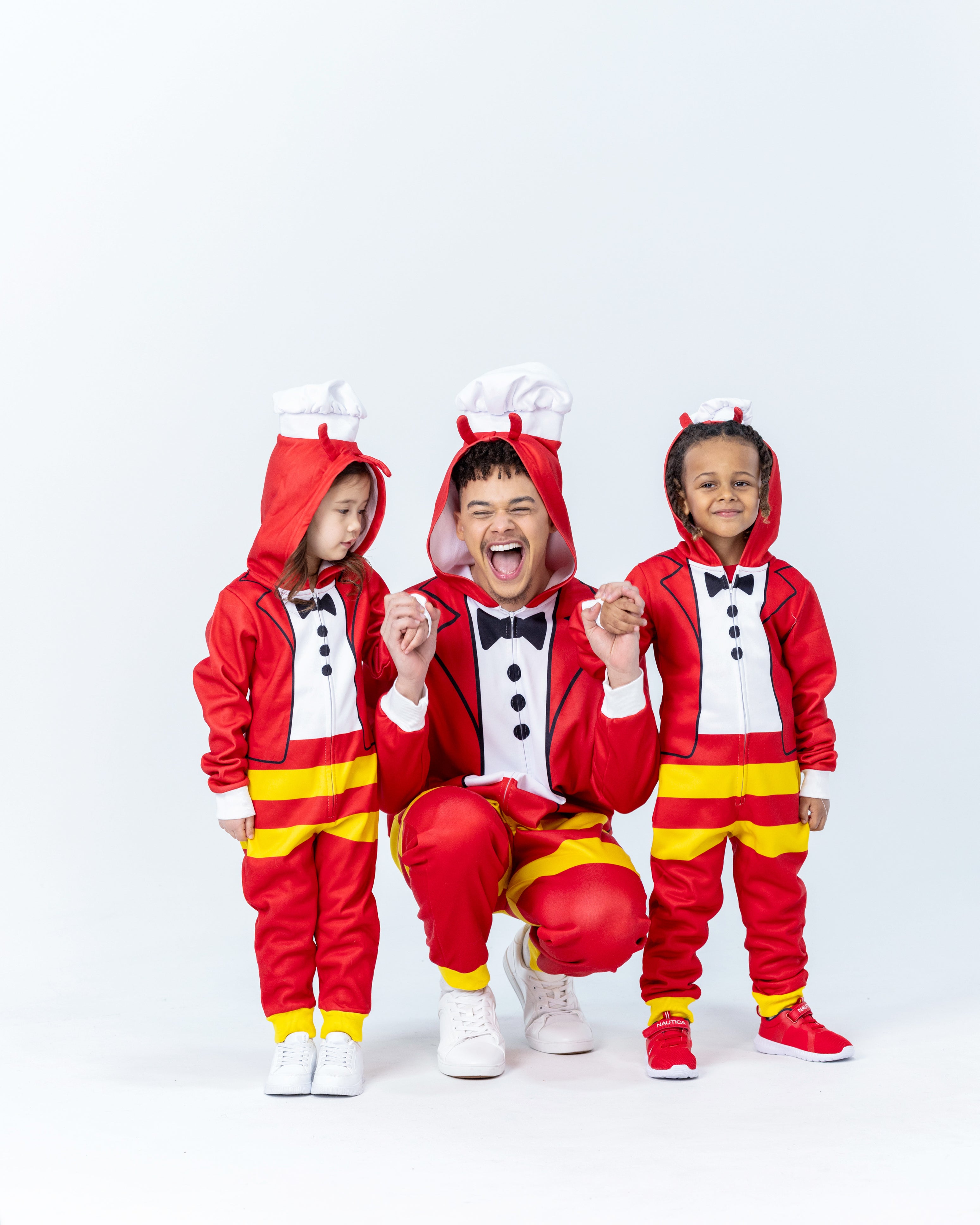 A person and two children in matching Jollibee red and yellow onesies with a white background